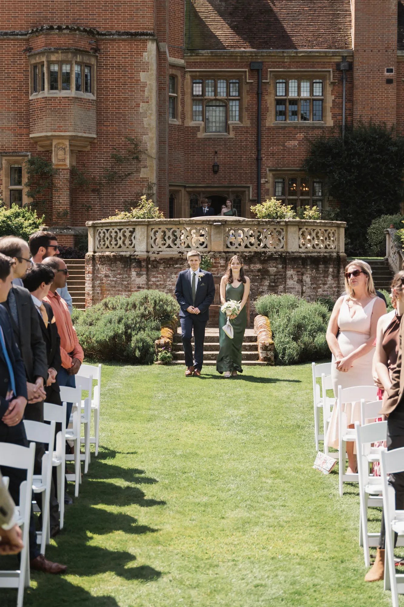 The wedding party walking down the aisle for the ceremony in the sunken garden at Lanwades Hall