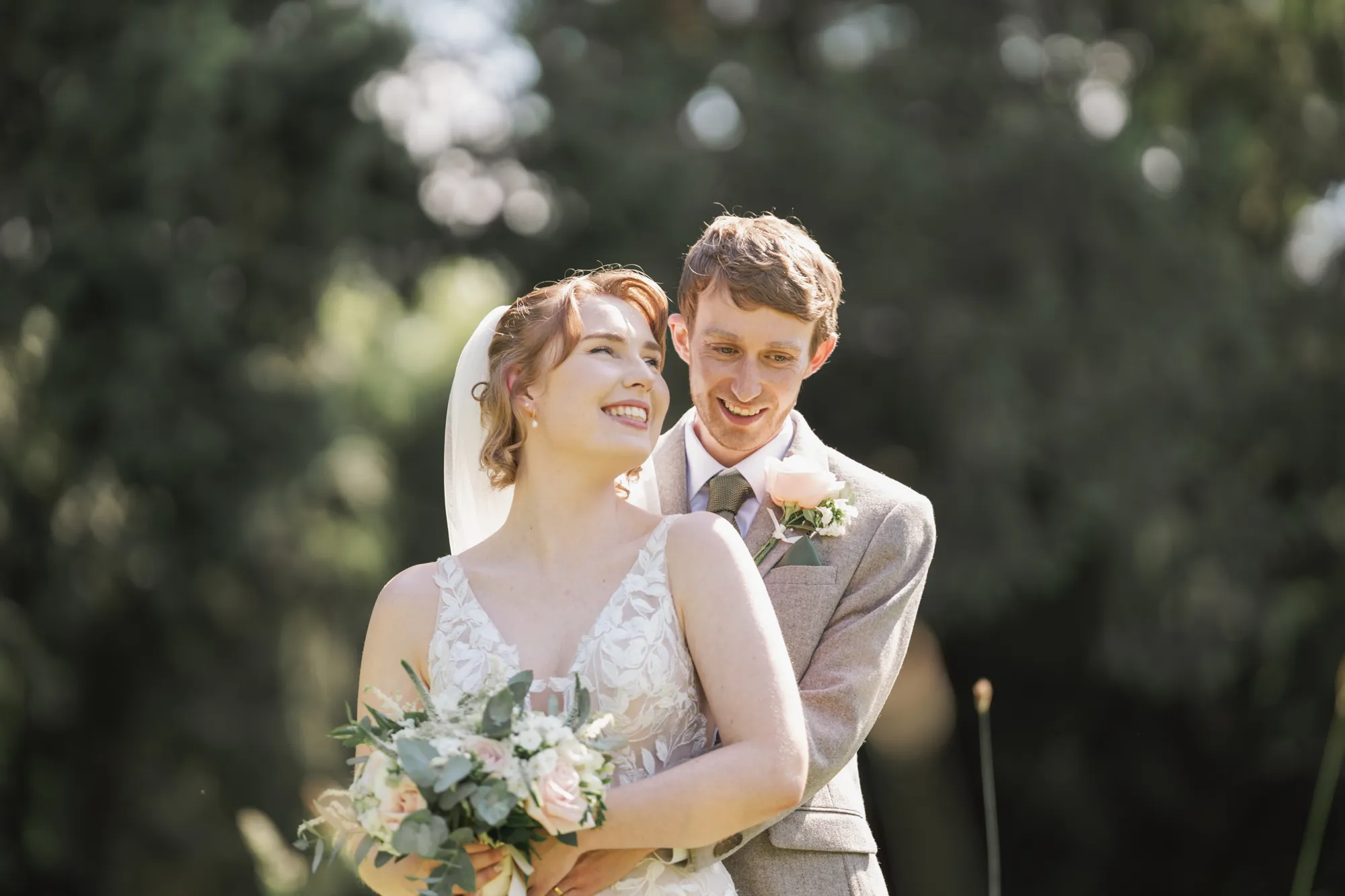 A bride and groom embracing in the summer garden at Lanwades Hall
