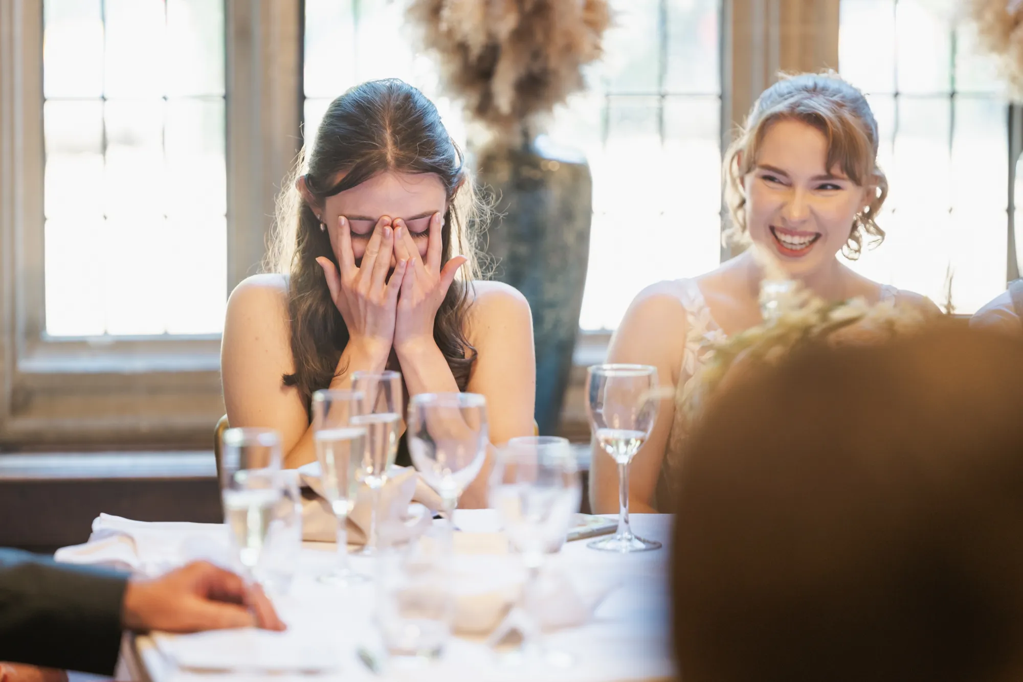 A bridesmaid laughing during the wedding speeches at Lanwades Hall
