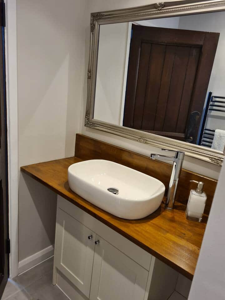 A modern bathroom with a stone basin and oak worktop in an apartment at Lanwades Hall