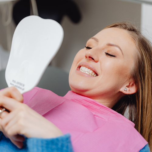 Patient checking her smile in a mirror after a dental visit