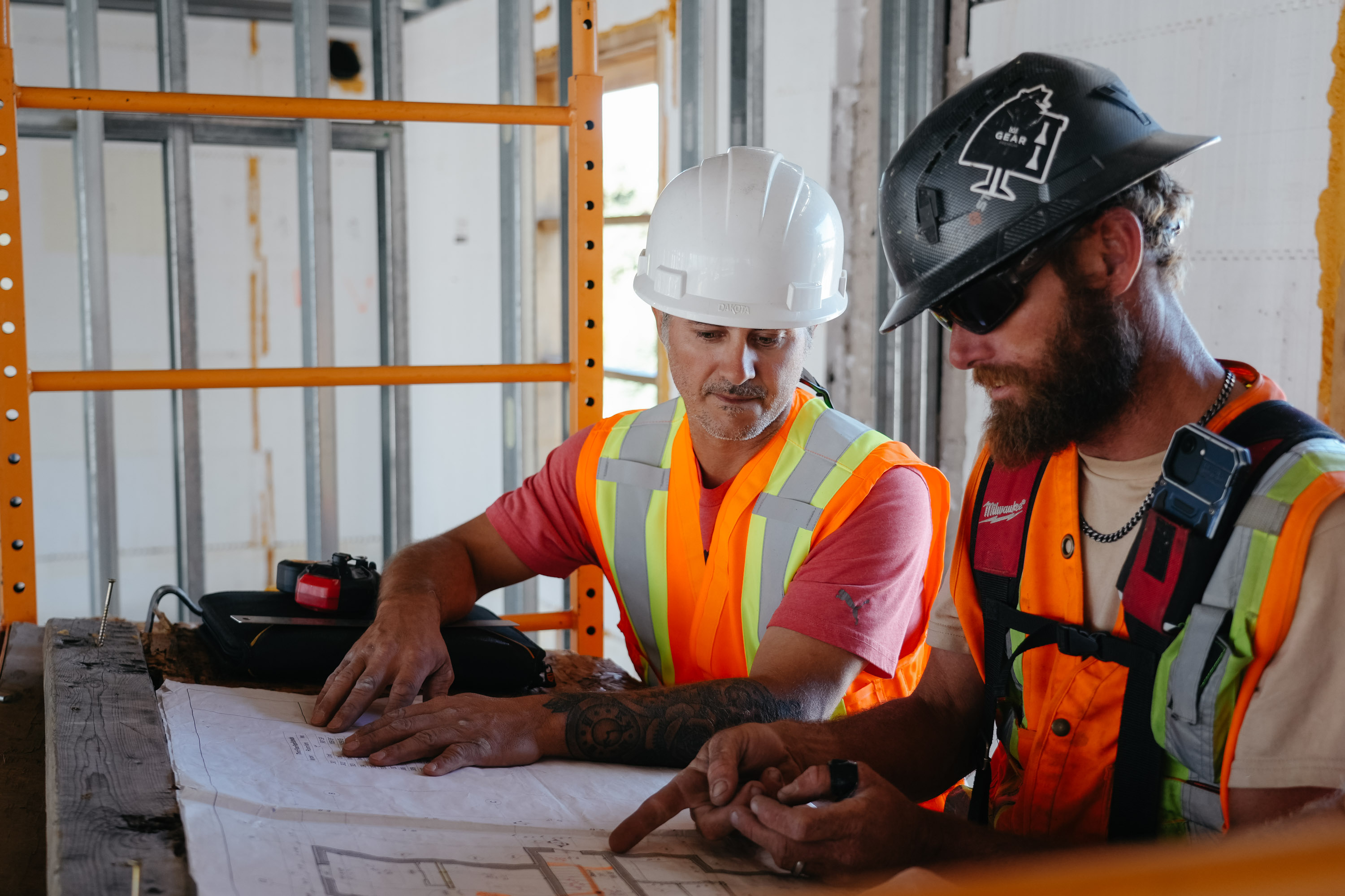 Two Blue Thunder Construction workers in safety vests analyzing project plans on a commercial construction site in Moncton.