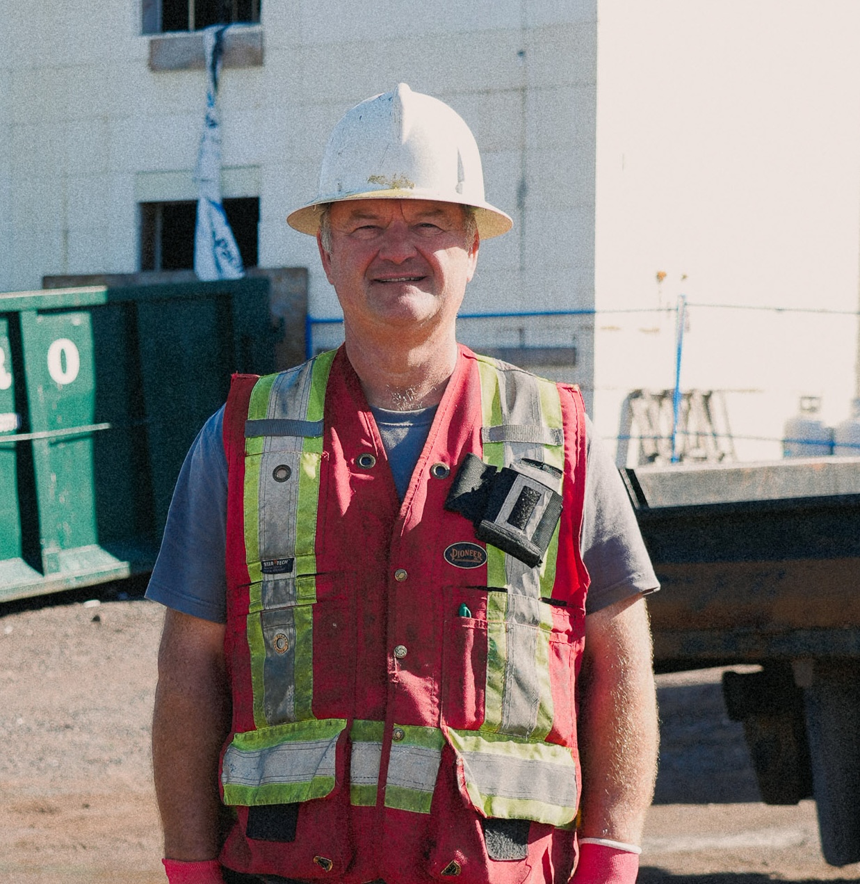 A Blue Thunder Construction site manager wearing a hard hat and red safety vest standing at a commercial job site in Moncton.
