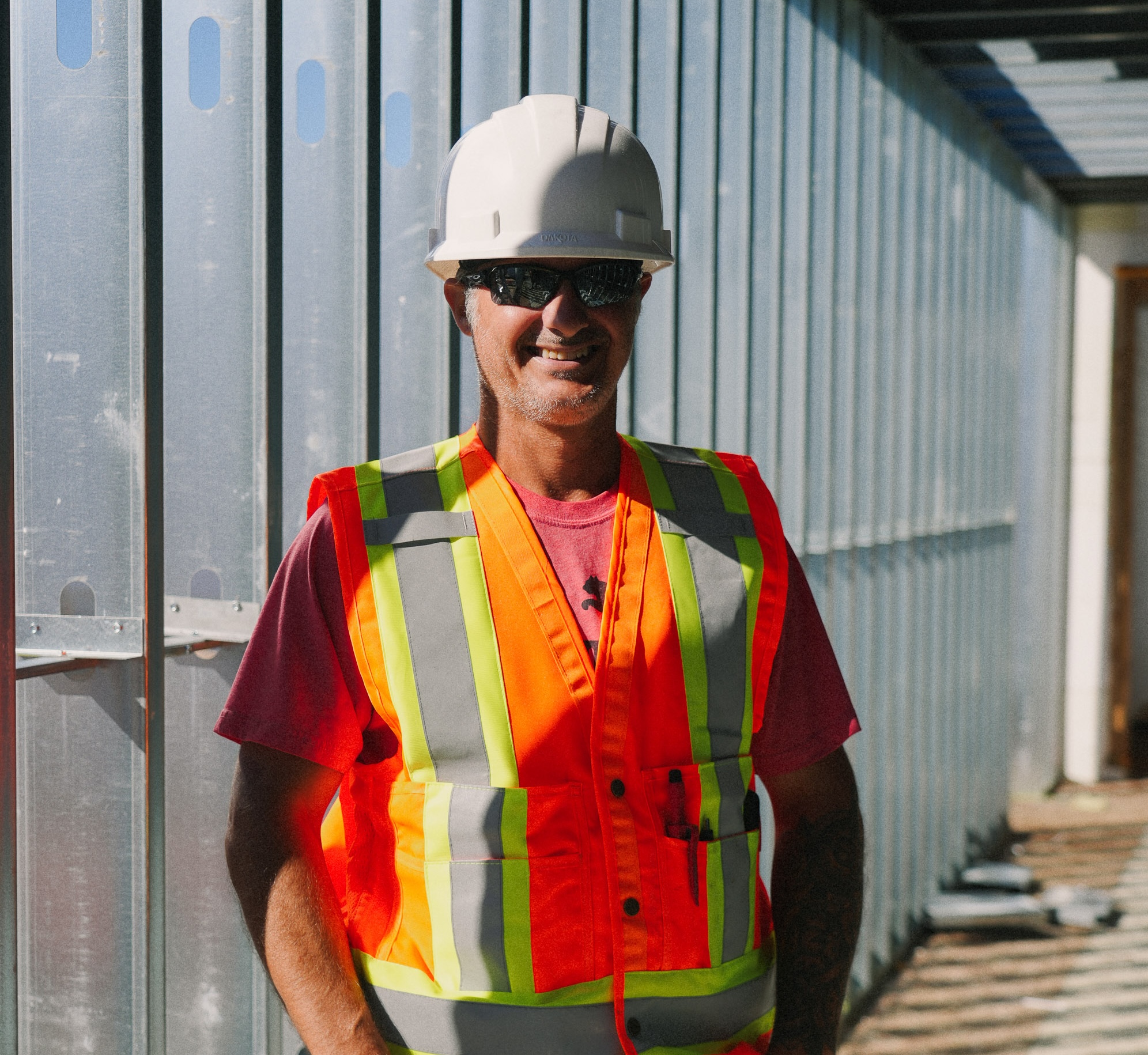 A smiling Blue Thunder Construction worker standing in a newly framed steel corridor at a construction project in Dieppe.