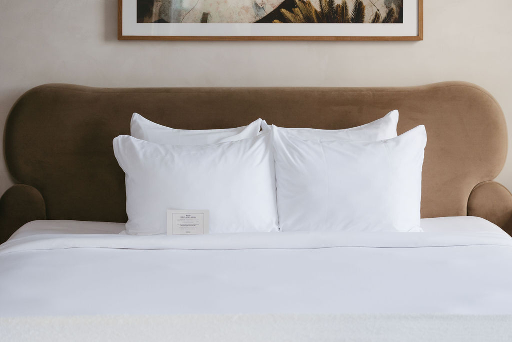 Crisp white pillows against a curved tan velvet headboard