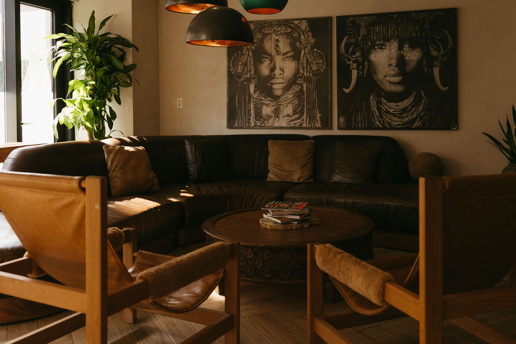 The lobby lounge, with a leather sectional beneath two large portrait canvases