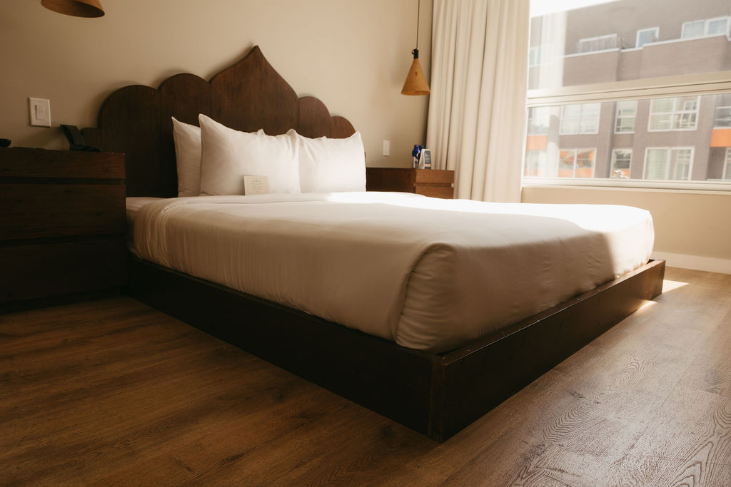 A guest room with a scalloped wood headboard and a low platform bed