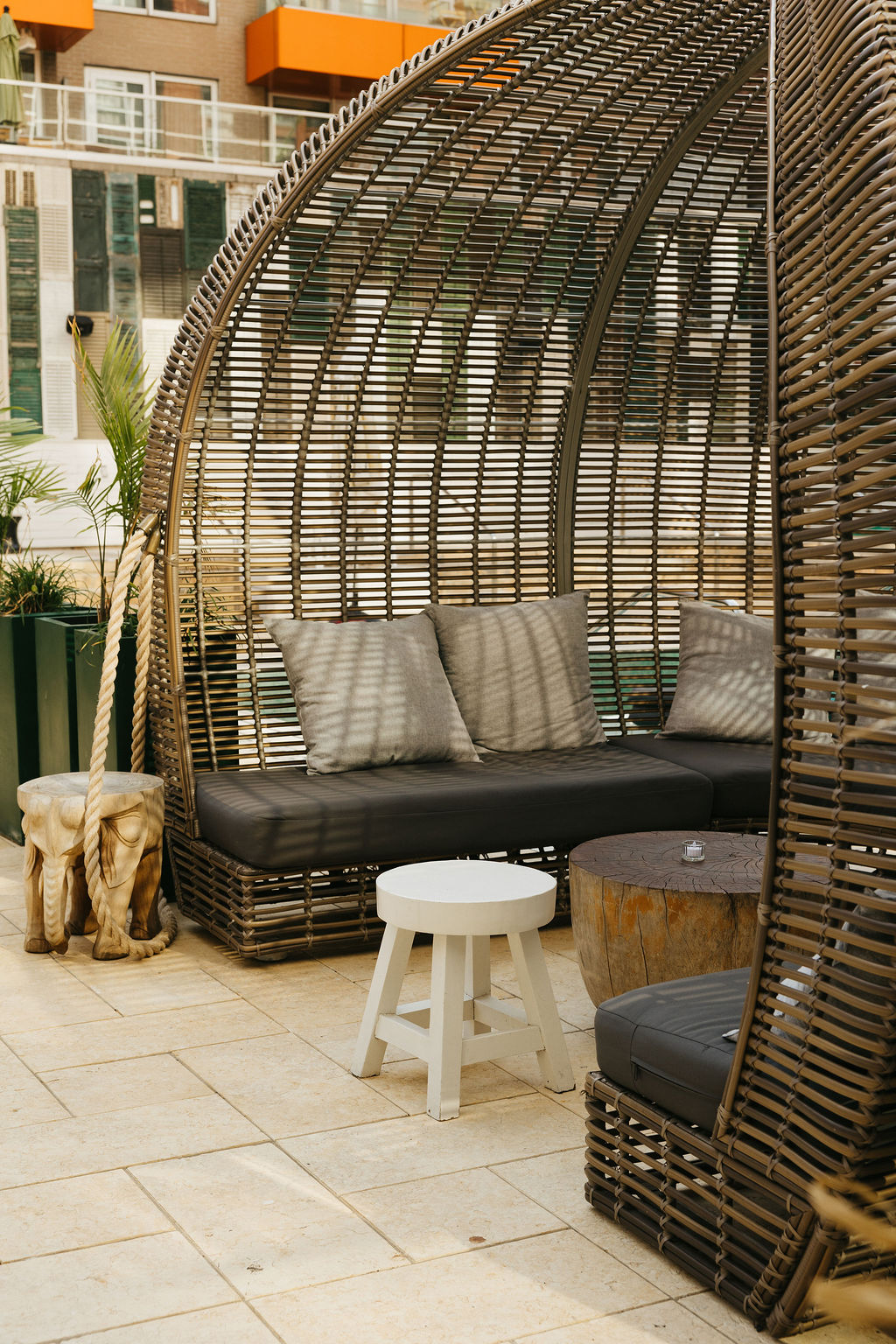 A woven cabana with cushioned seating on the pool terrace