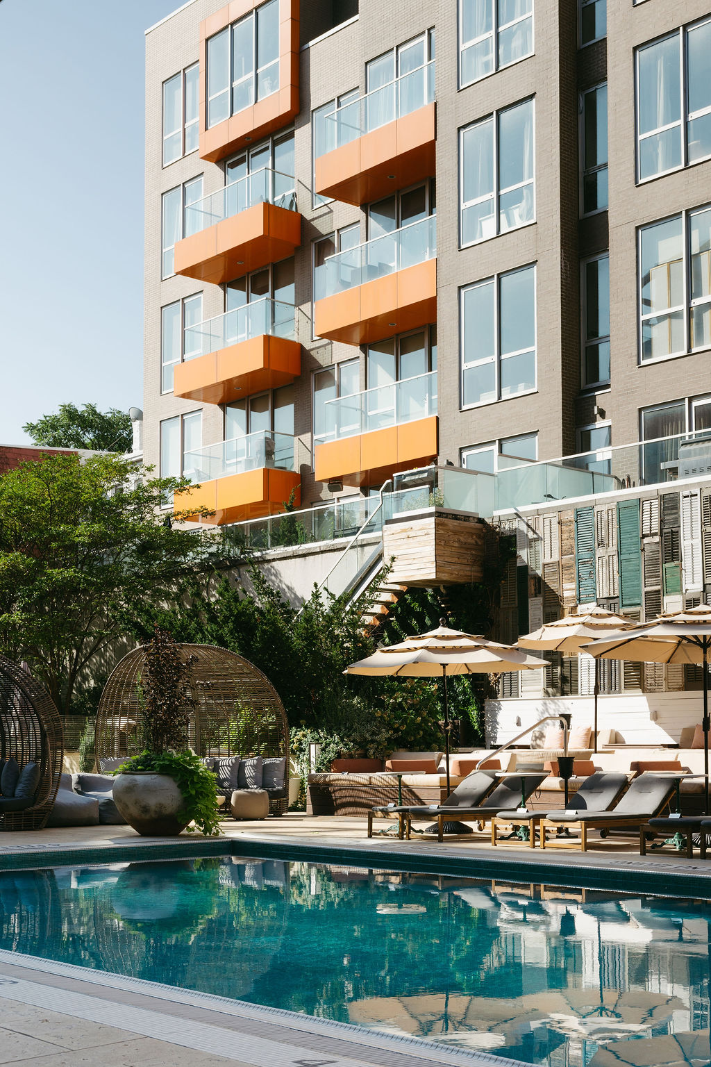 The outdoor pool, with loungers and umbrellas below the hotel's orange balconies