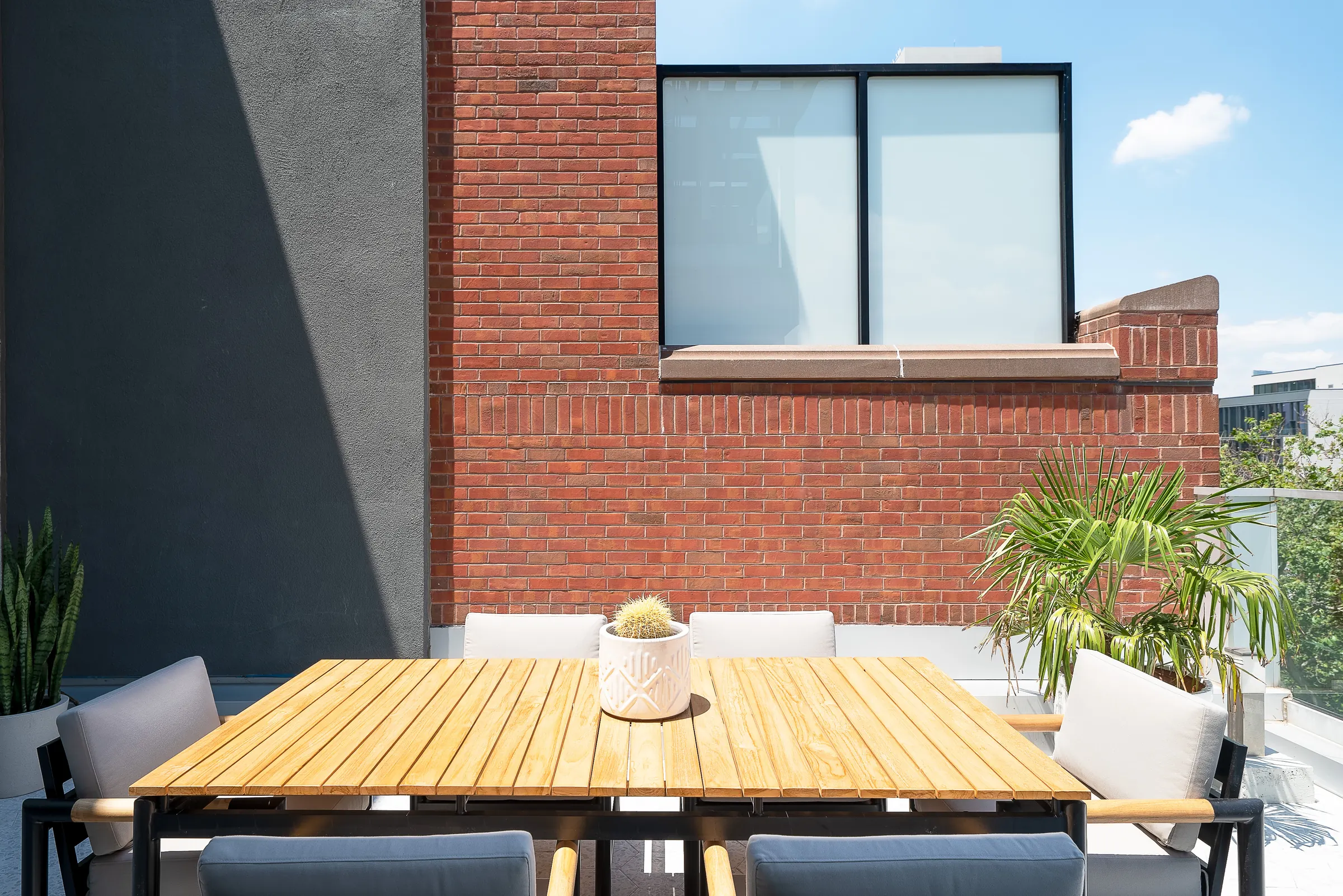 The terrace dining table for six, against the building's brick wall