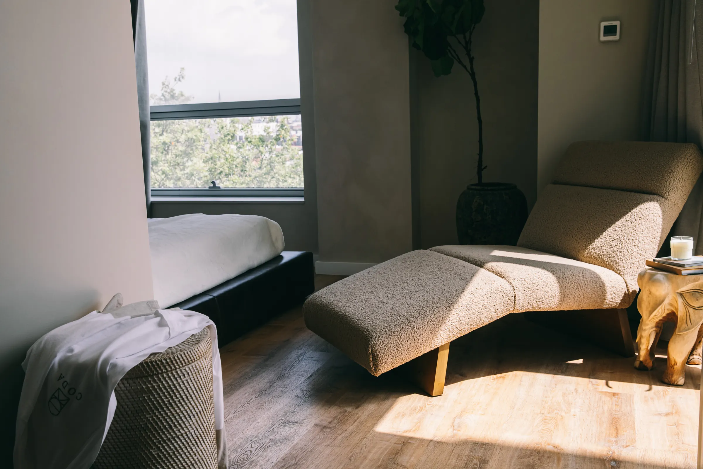 A bouclé chaise longue in the morning light beside the bed