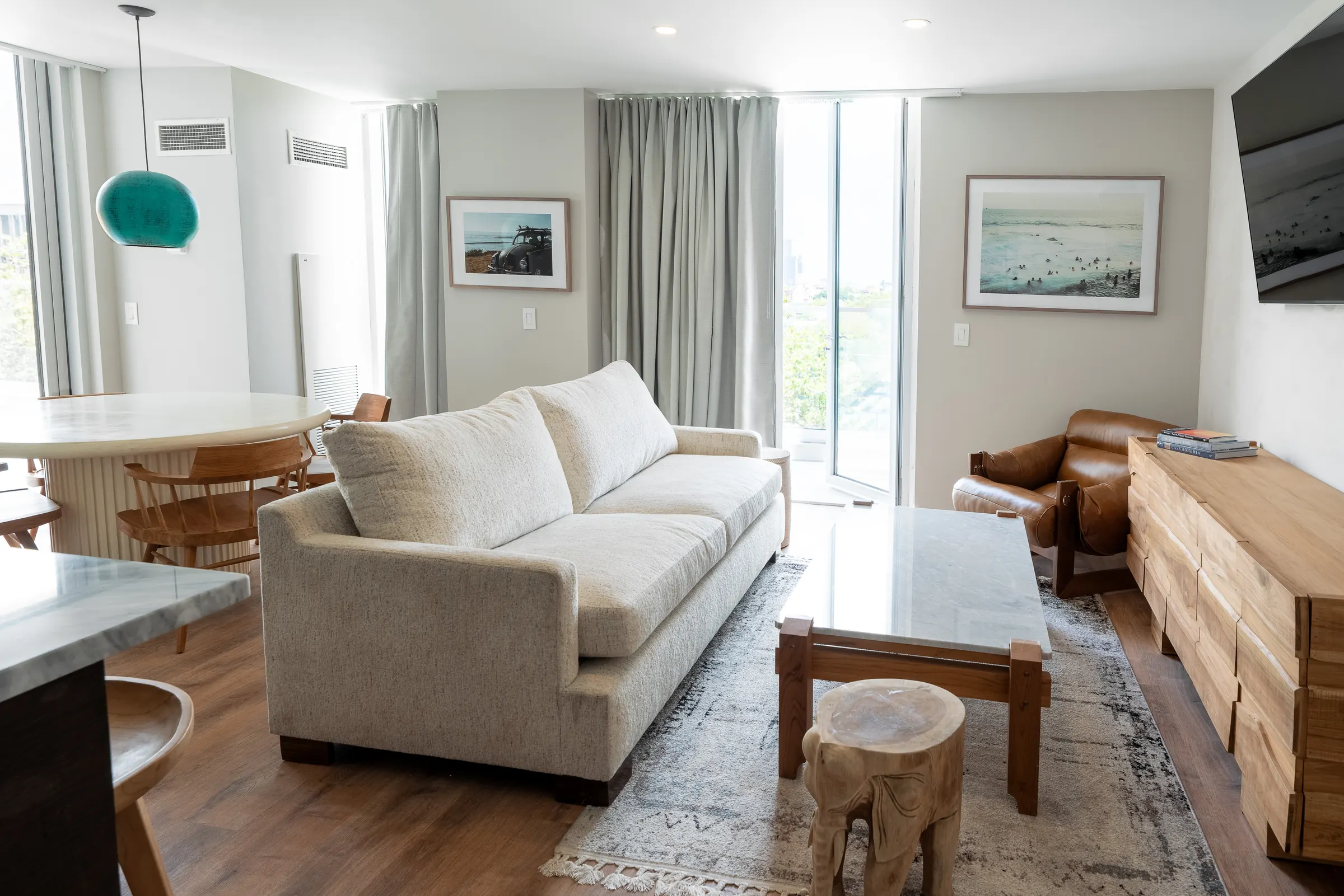 The suite living room, with a pale sofa, dining table and floor-to-ceiling windows