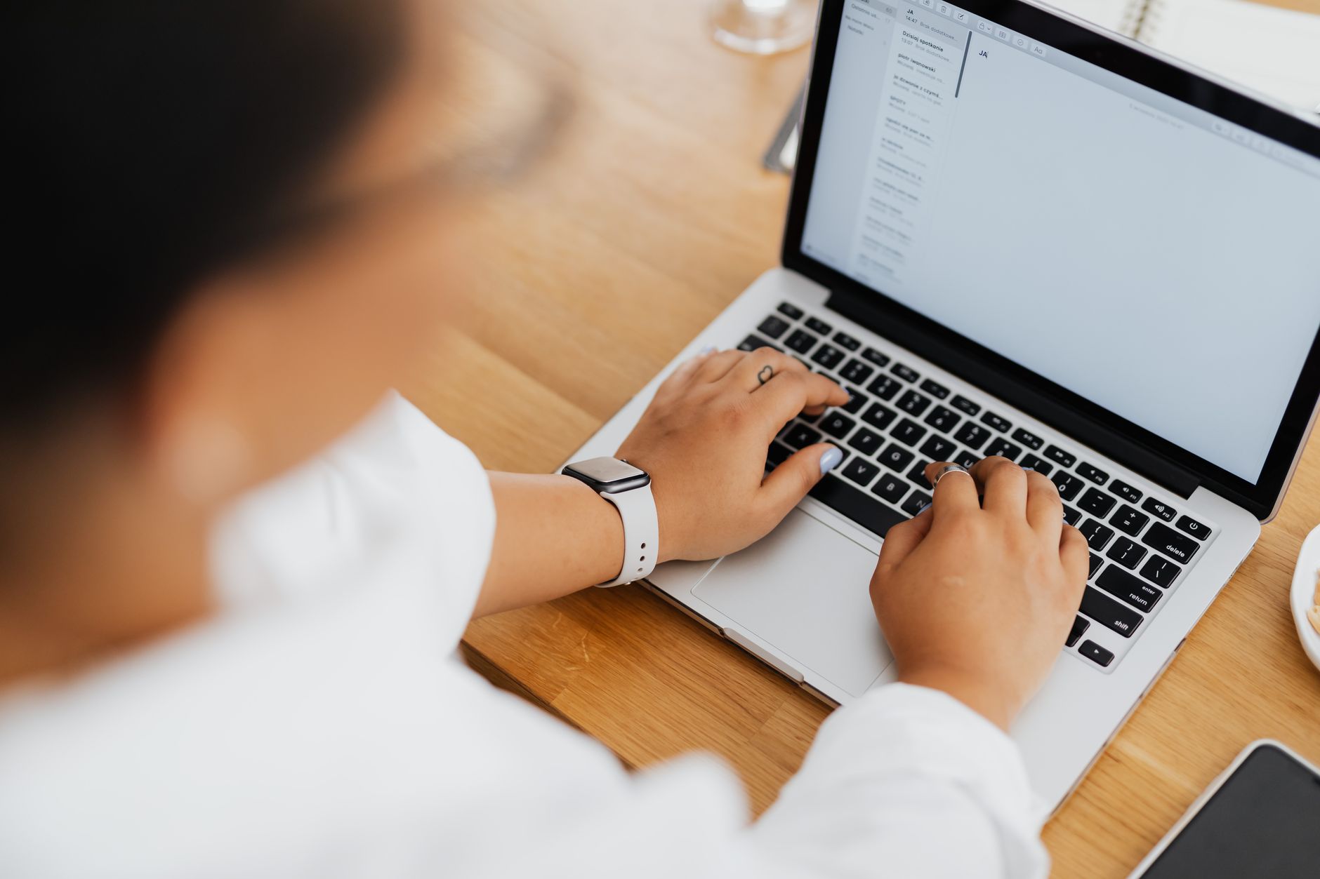 High angle shot of a person typing on a laptop, focused on hands and keyboard.