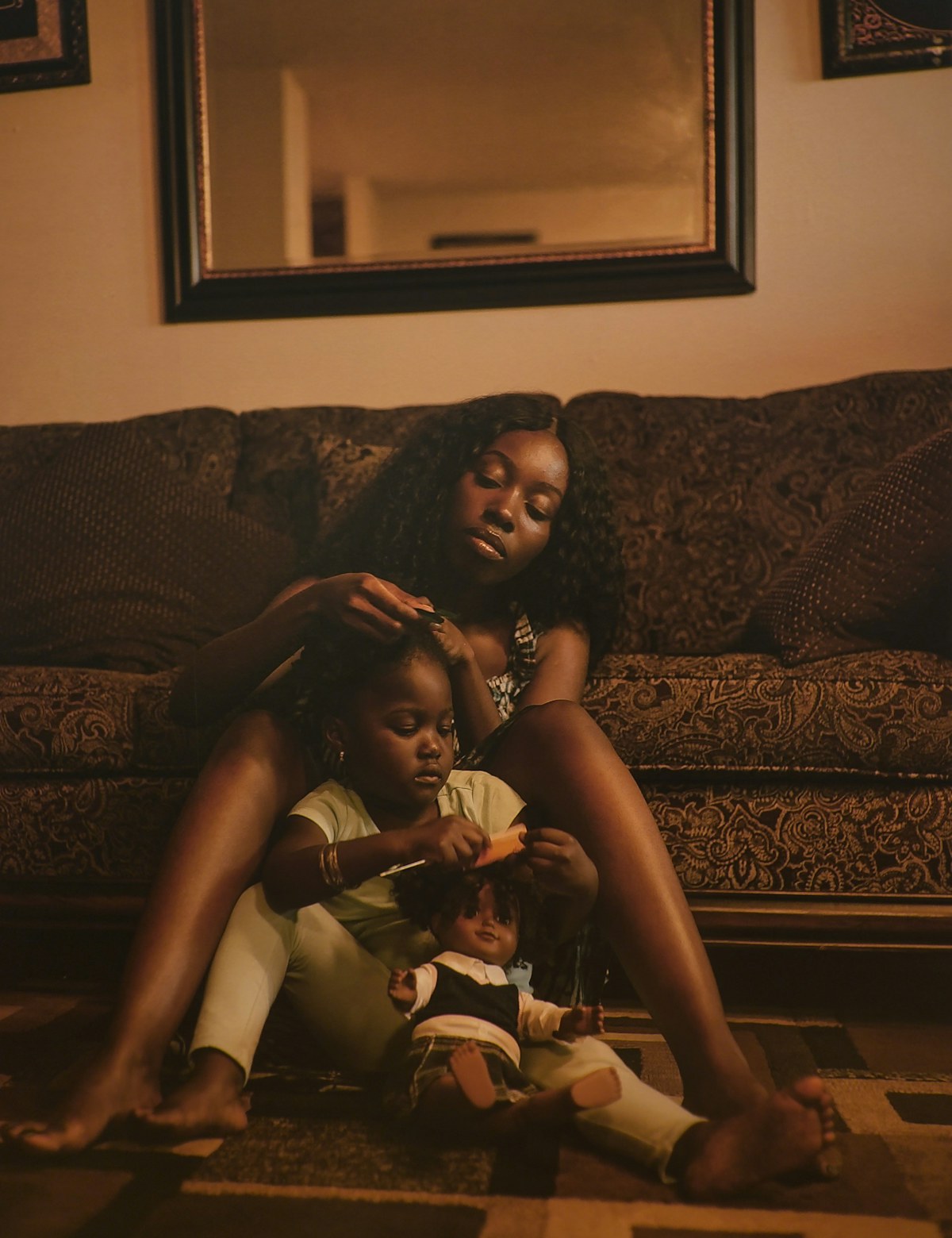 A mother doing her daughter's hair in their living room