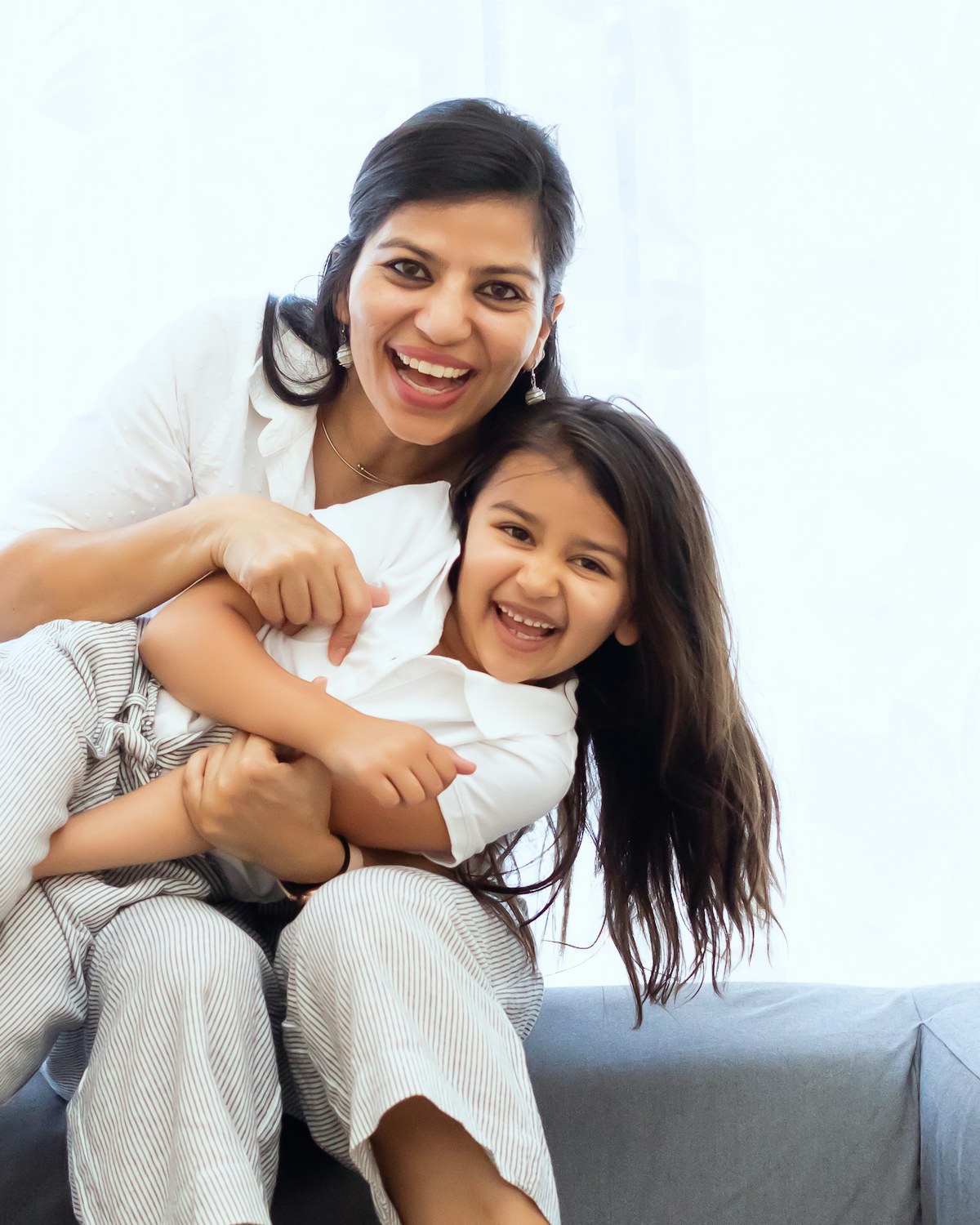 A mother and her daughter laughing together on the couch