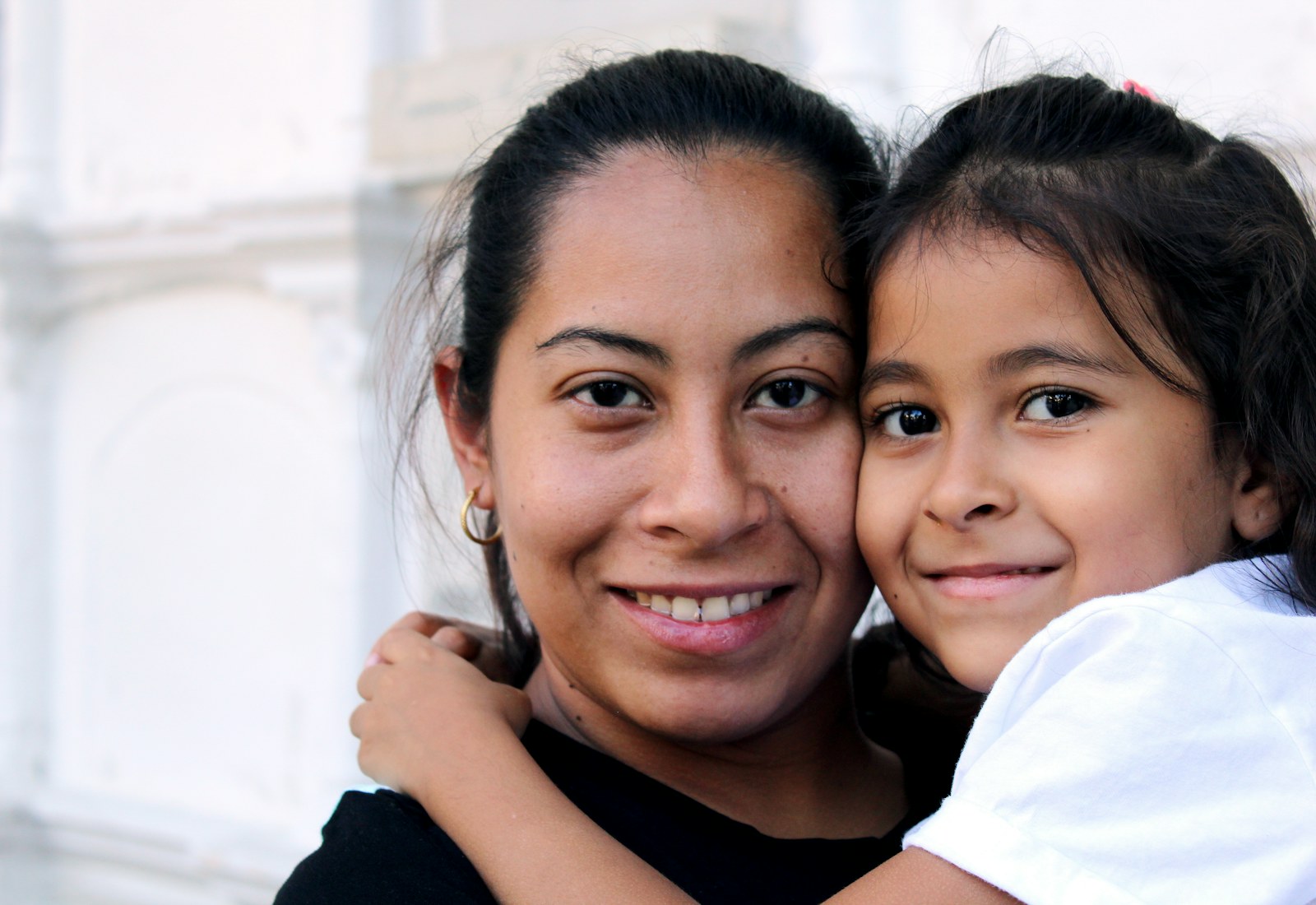 A mother and daughter cheek to cheek, smiling