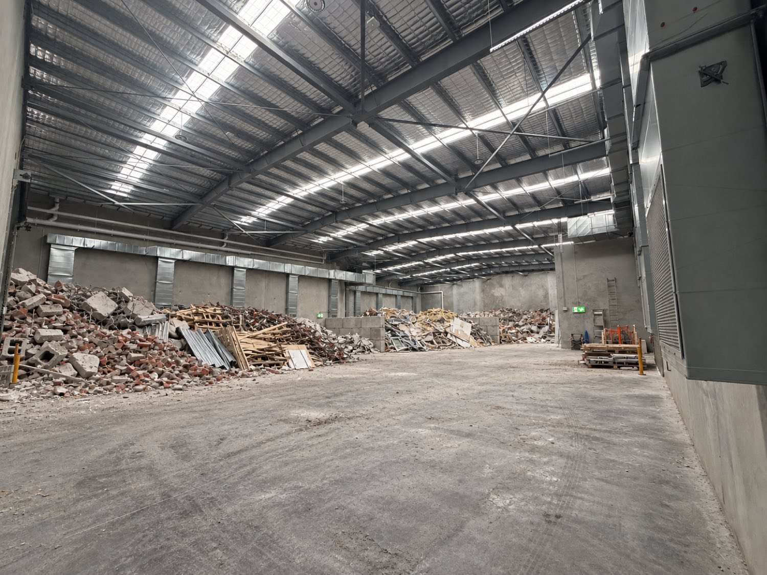 Construction and demolition waste separated into concrete, timber and metal piles on the sorting floor at APEX Recycling