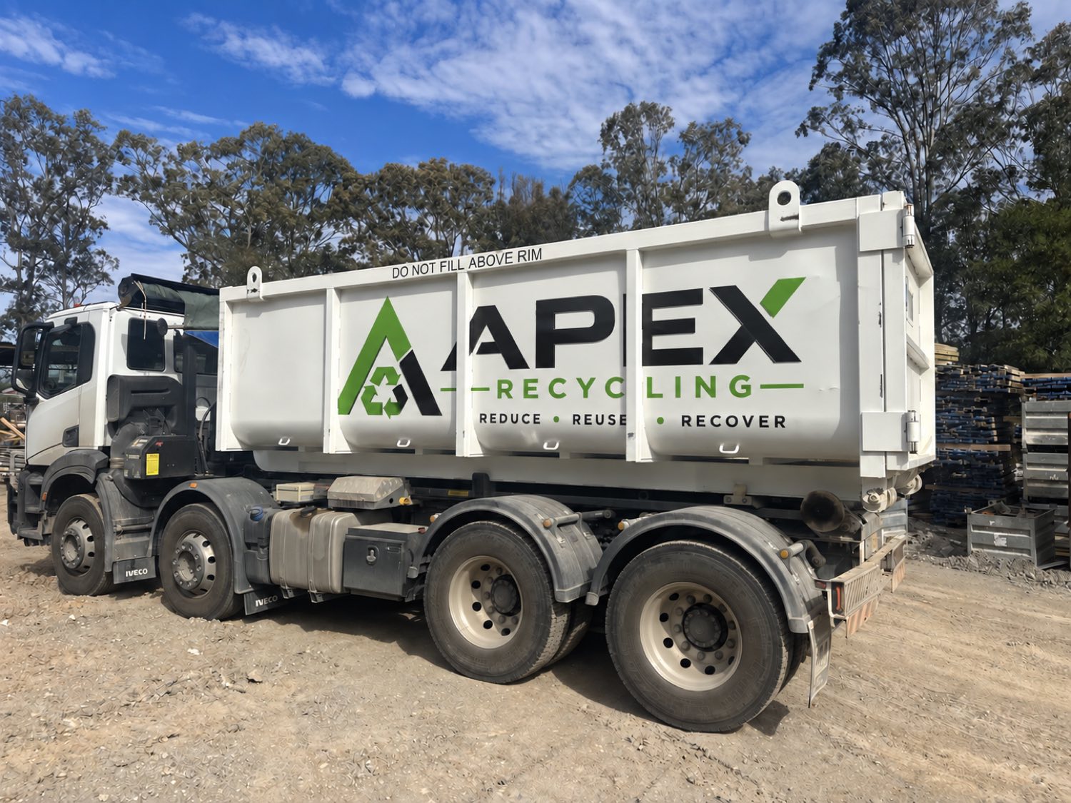 An APEX Recycling hook lift truck loaded with a branded hook bin