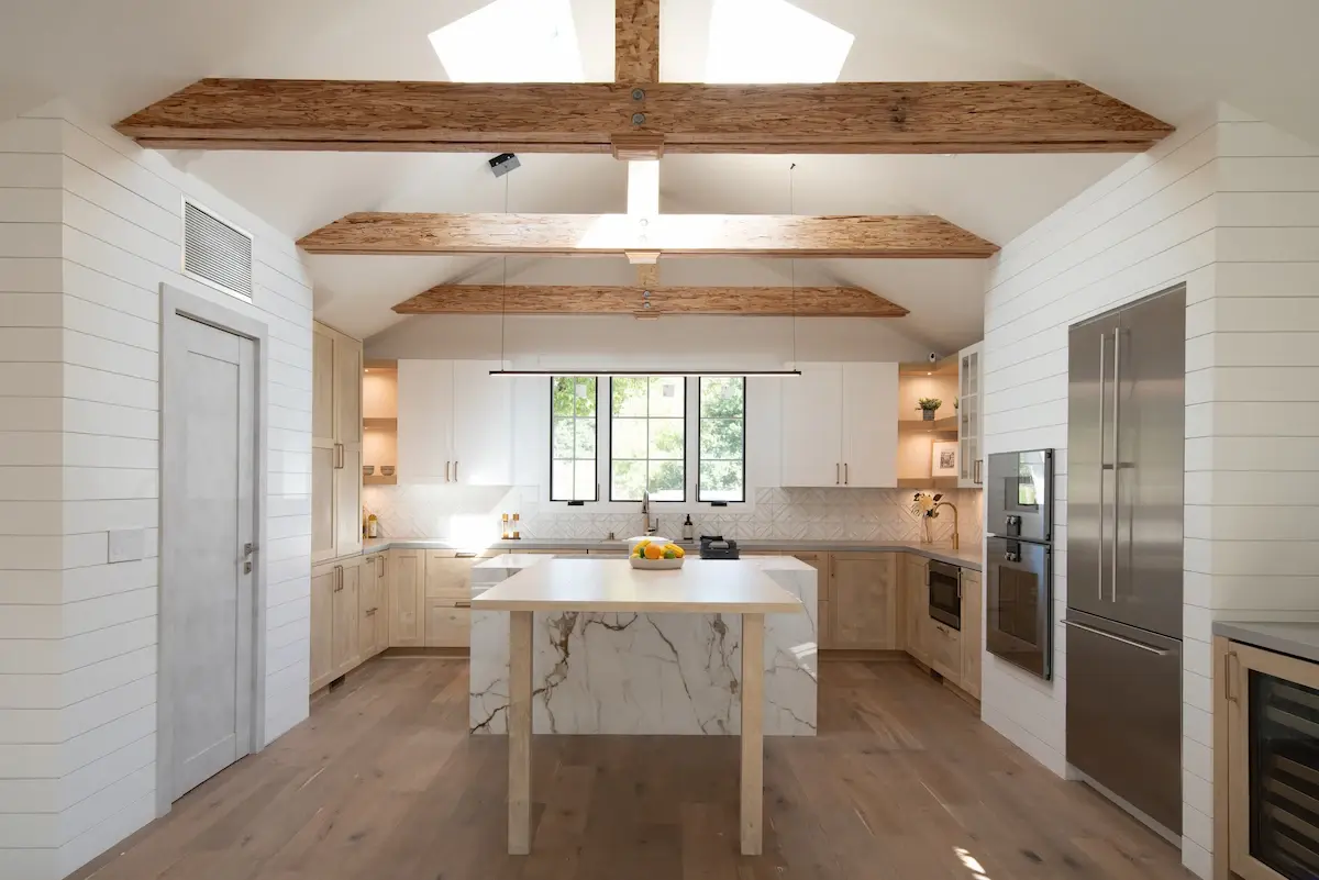 Springer in Los Altos features a spacious kitchen with a cathedral ceiling, skylights, and wood beams, centered around a marble island.