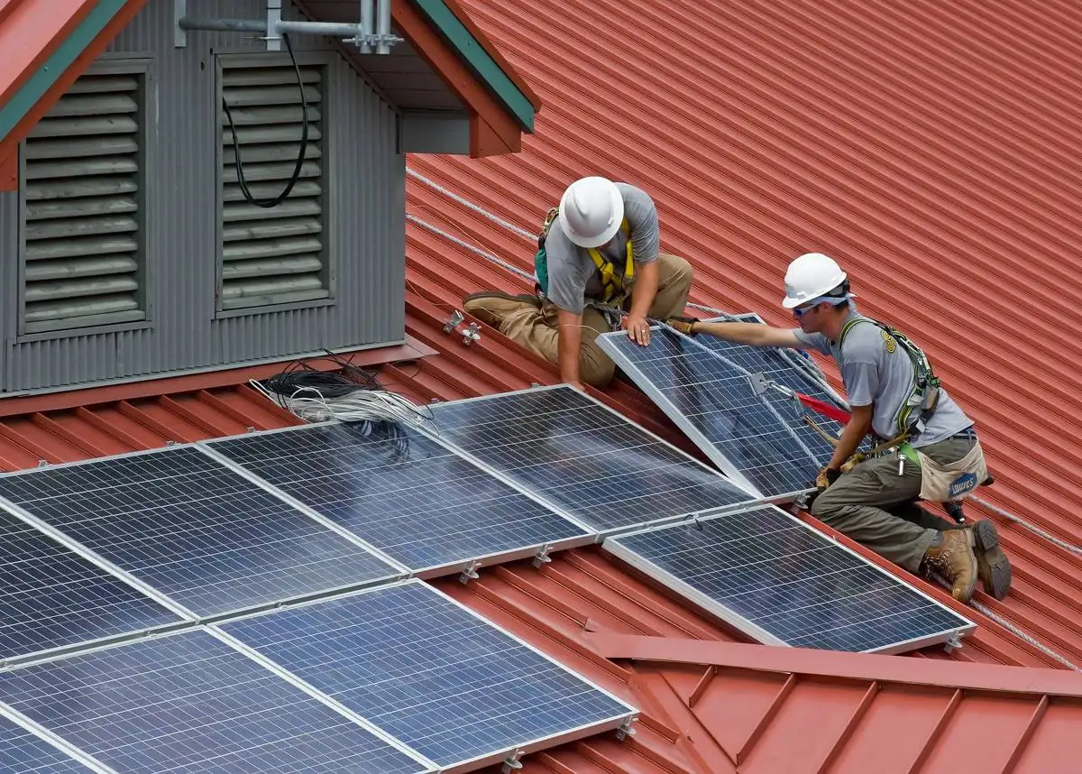 Professional contractors installing rooftop solar panels during a sustainable energy home construction project.