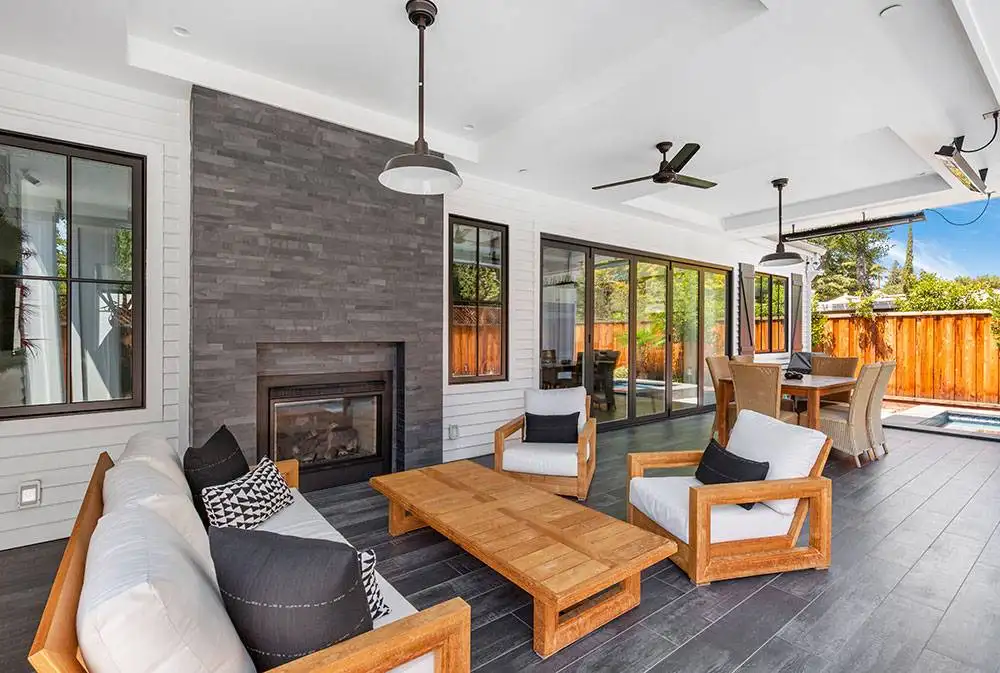 Custom luxury outdoor living space with a built-in stone fireplace and modern patio furniture, built as part of a Bay Area home construction project."