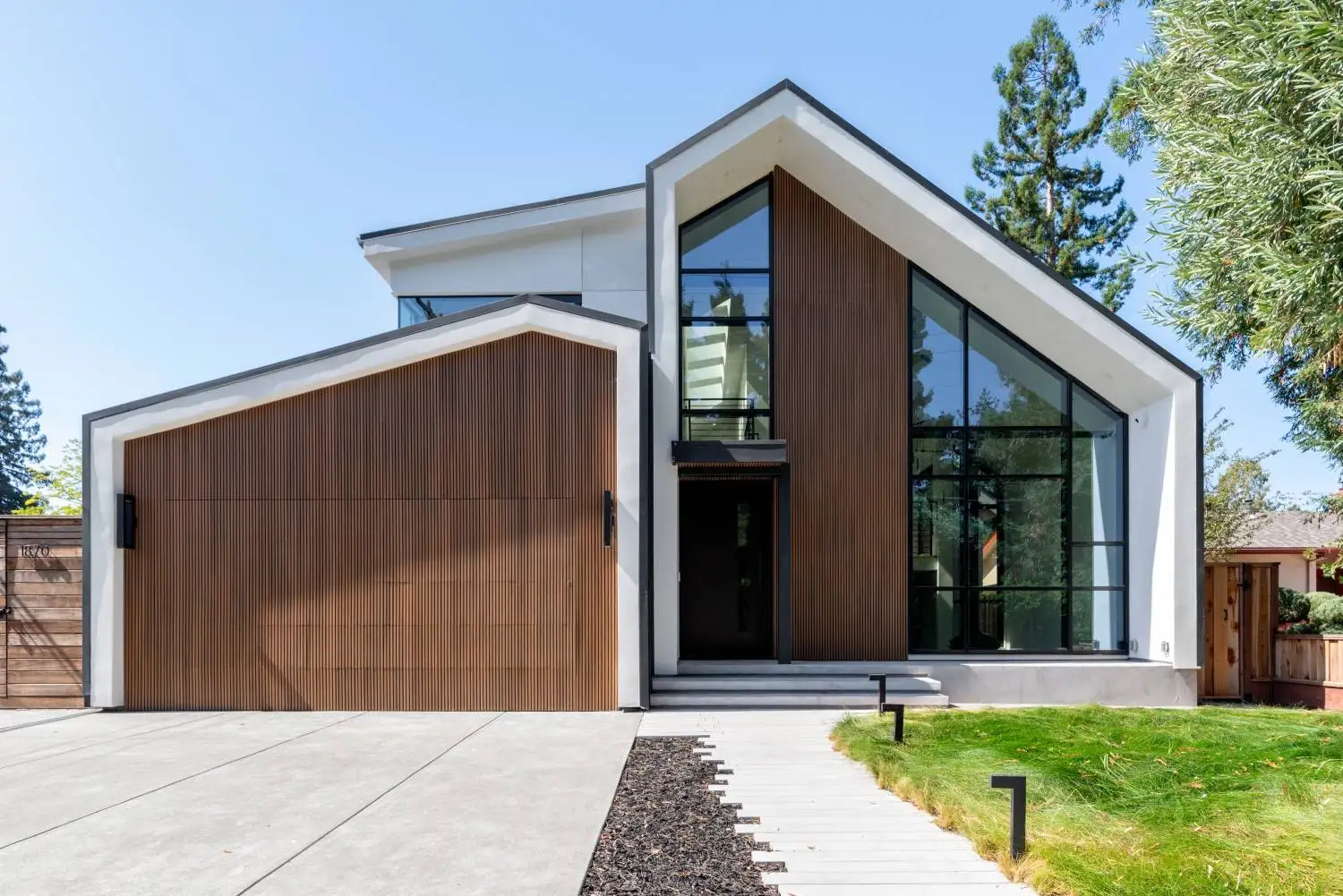 Modern two-story home exterior with a vertical wood slat garage door and a steep gabled roofline