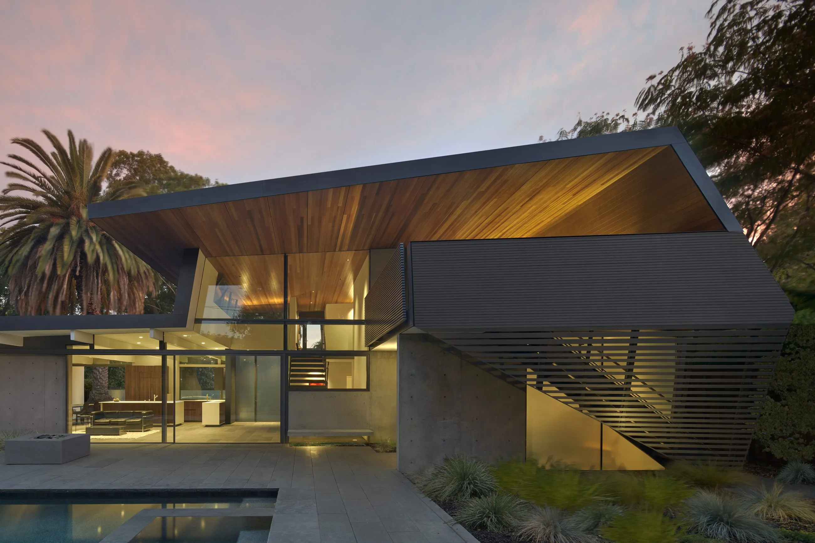 Greenberg’s Edgewood Drive new-build home in Palo Alto, with an angular roof and wood soffit at dusk