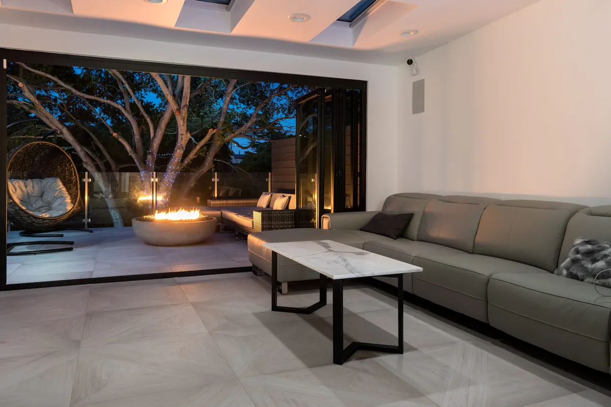 Greenberg remodel living room opening through folding glass doors to an outdoor seating area