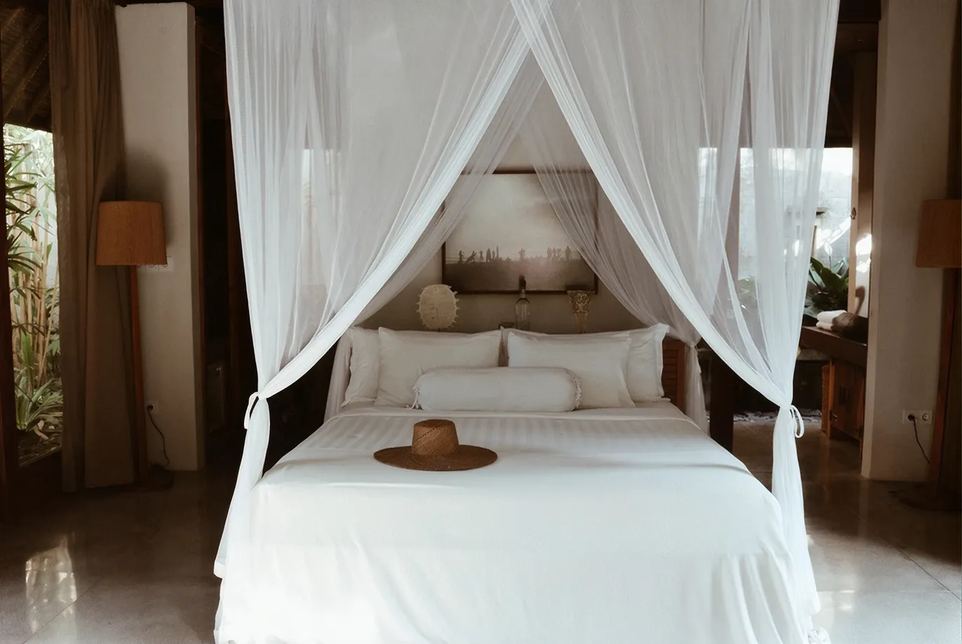 Straw hat on a freshly made canopy bed