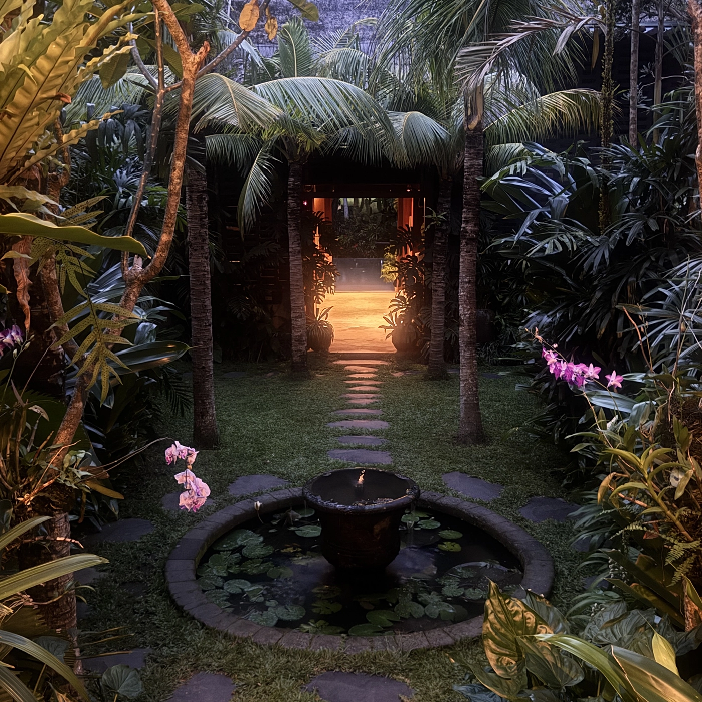 Lit garden path and stone fountain after dark