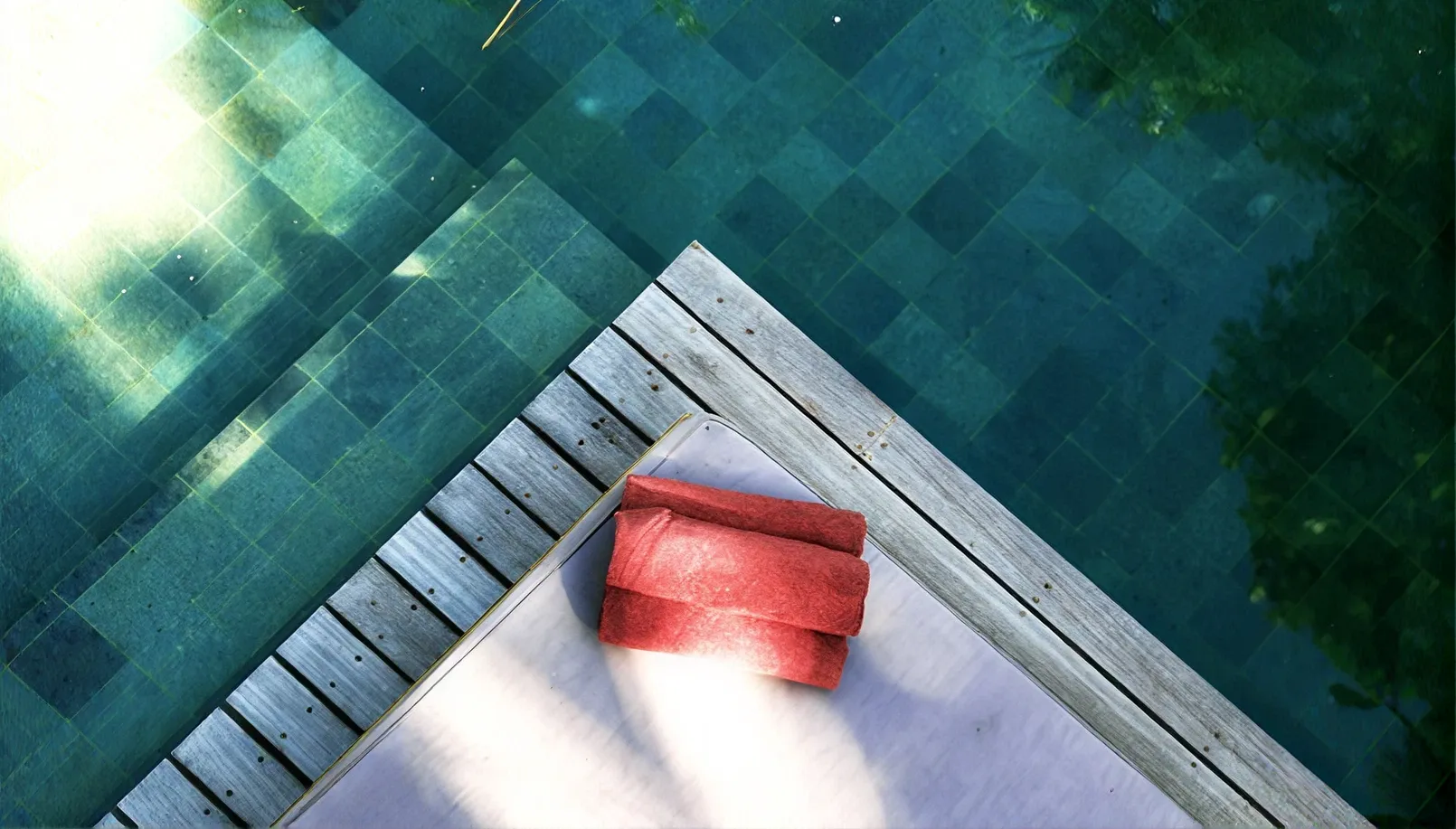 Towel folded at the pool's teal edge