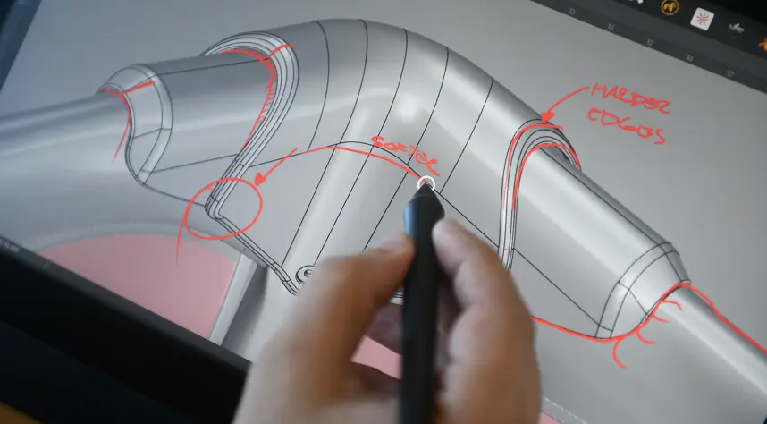 A hand holding a stylus is sketching red annotations on a 3D digital model of a curved, tubular object displayed on a tablet screen.