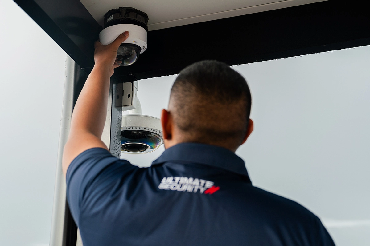 Ultimate Security technician installing a commercial CCTV surveillance dome camera.
