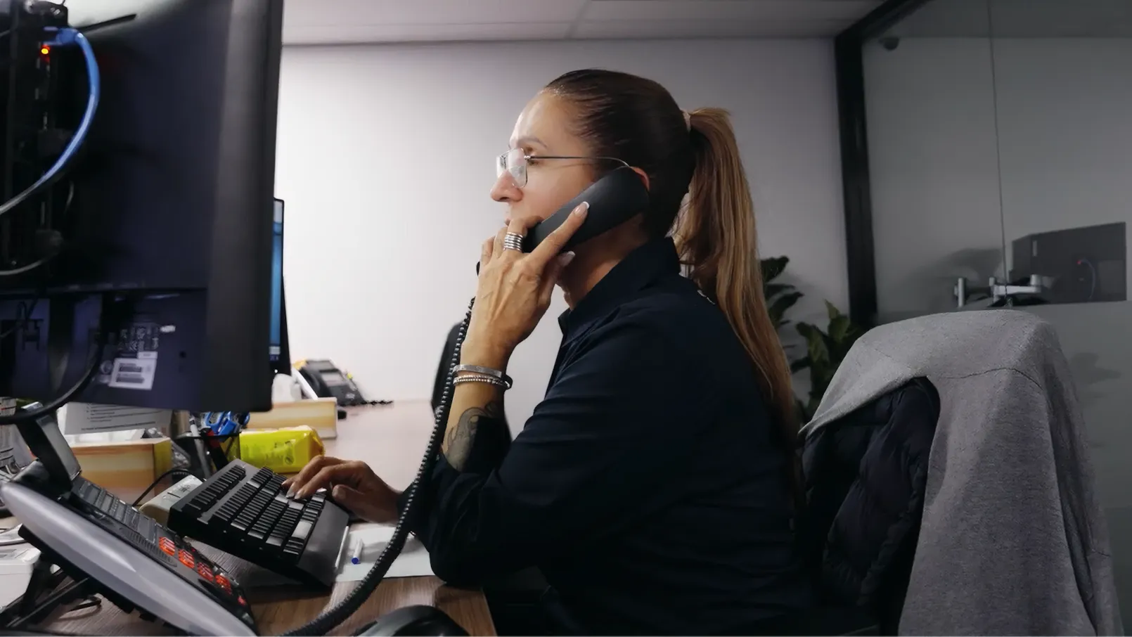 Ultimate Security female staff member managing a call and monitoring data on her monitor