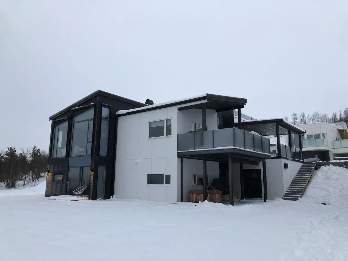Nyoppført enebolig i to plan med snø rundt.