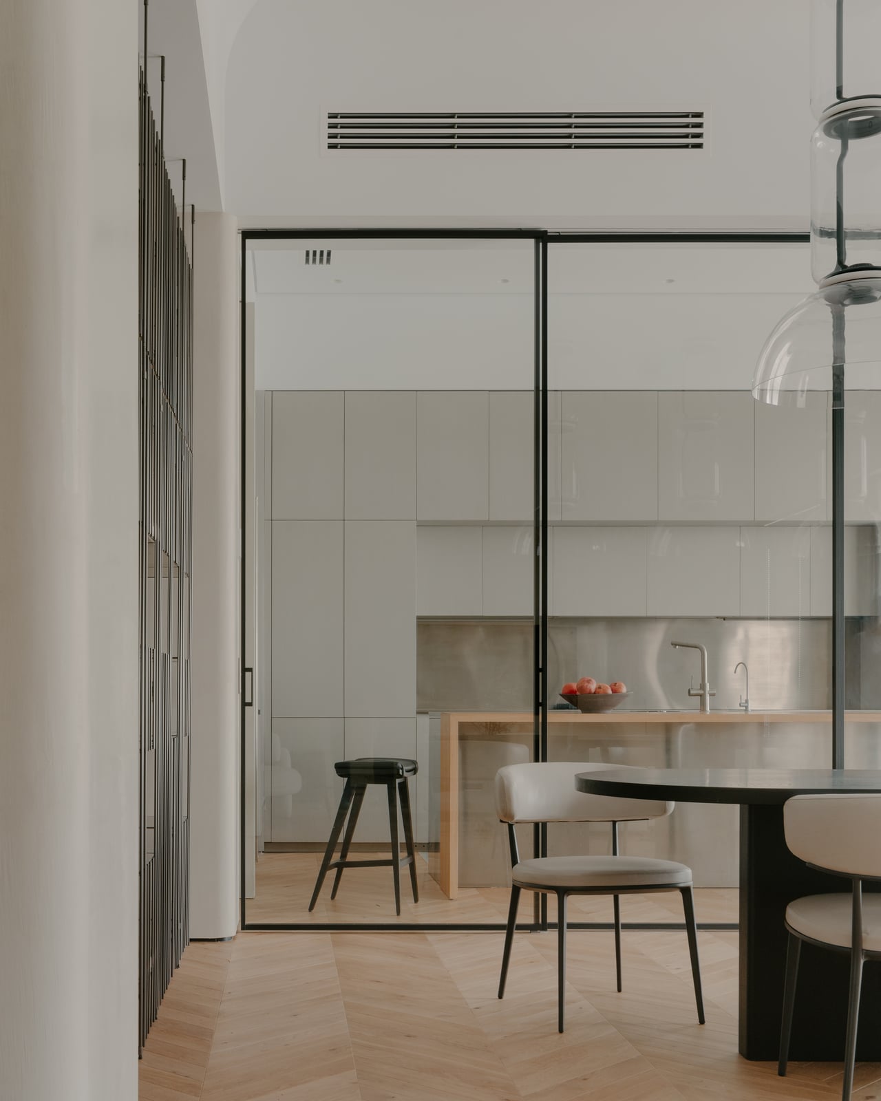View through a glazed partition to the dining table and kitchen stools