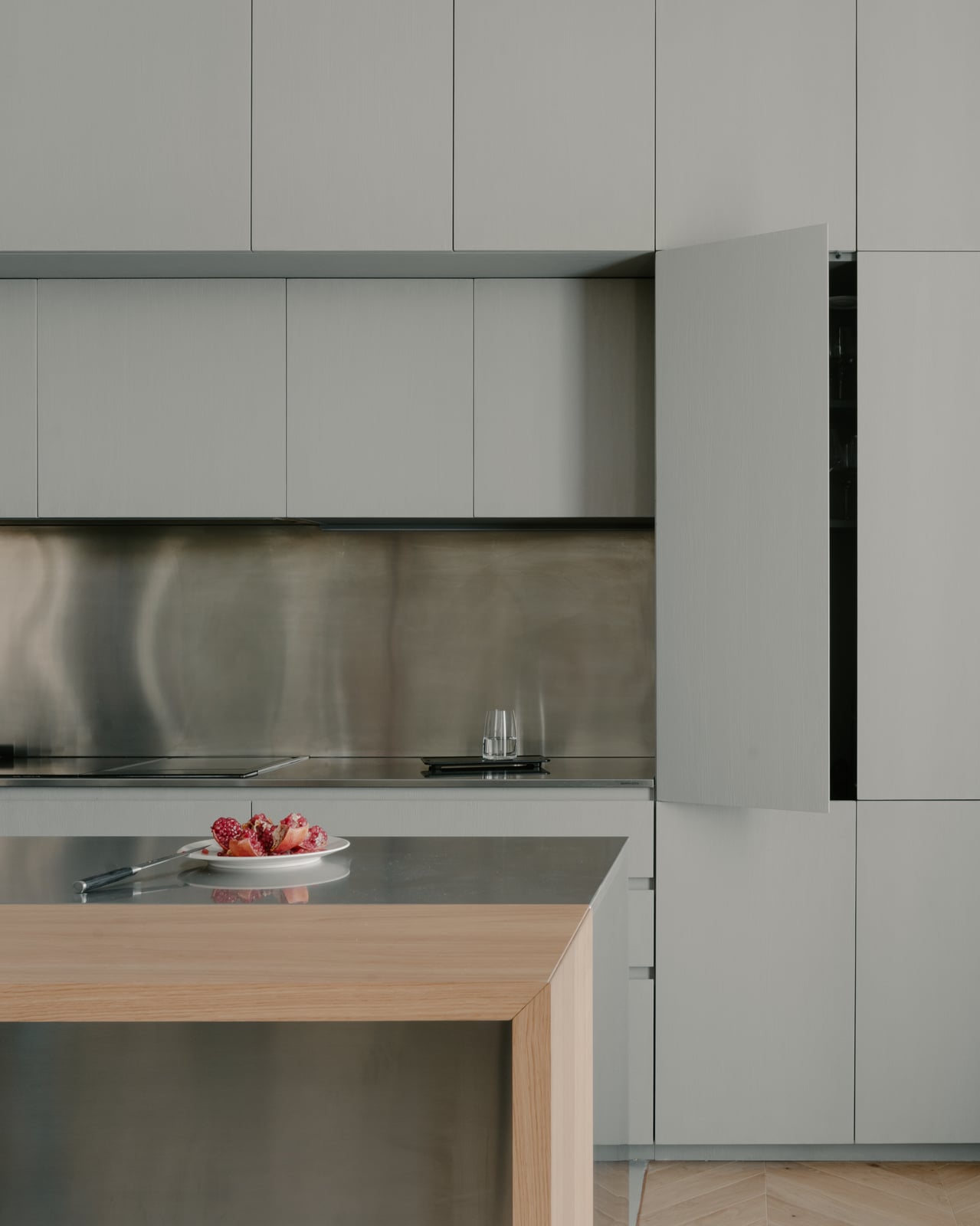 Kitchen with pale cabinetry, a wooden counter and a stainless steel splashback