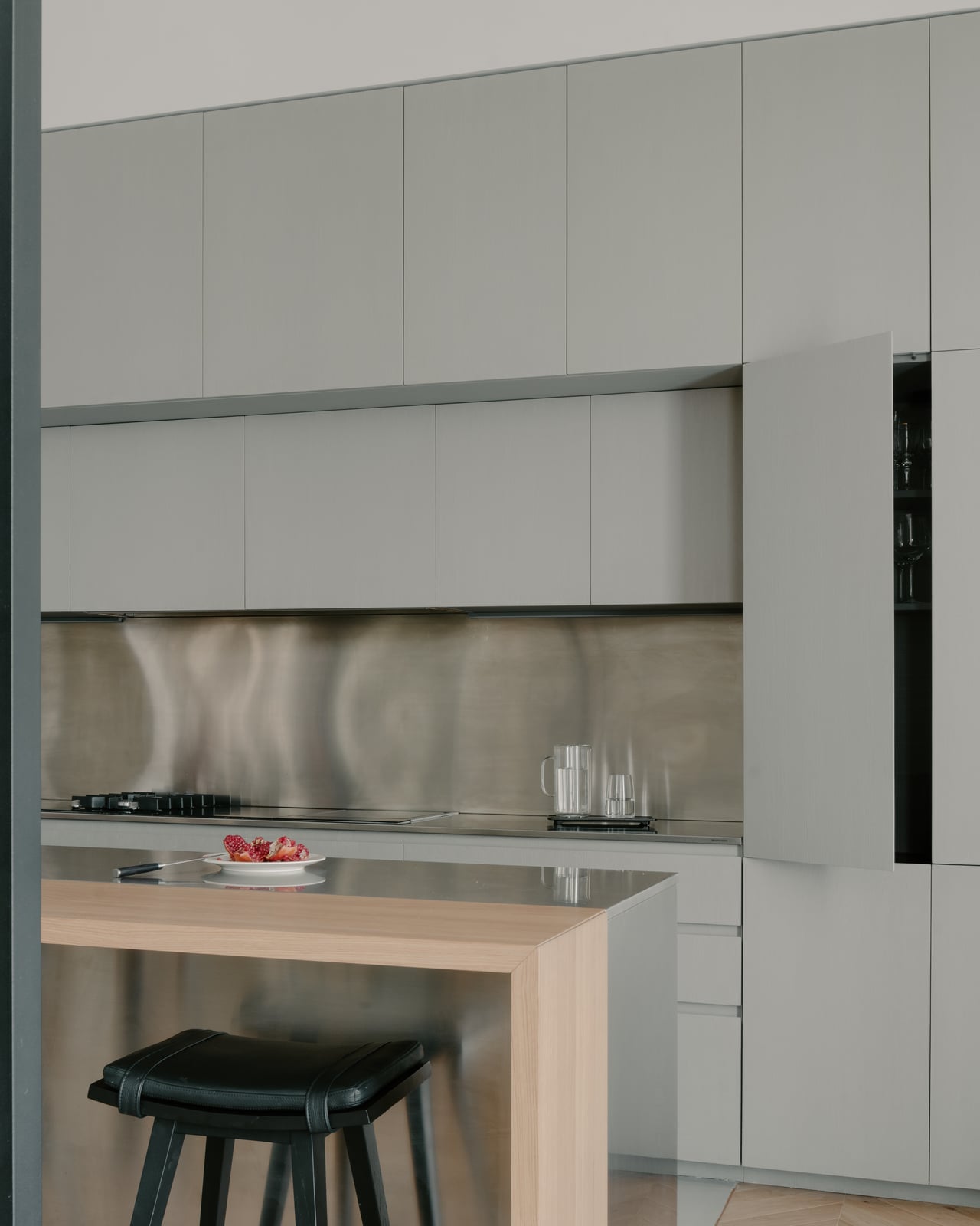 Kitchen island and cooking zone against a stainless steel splashback