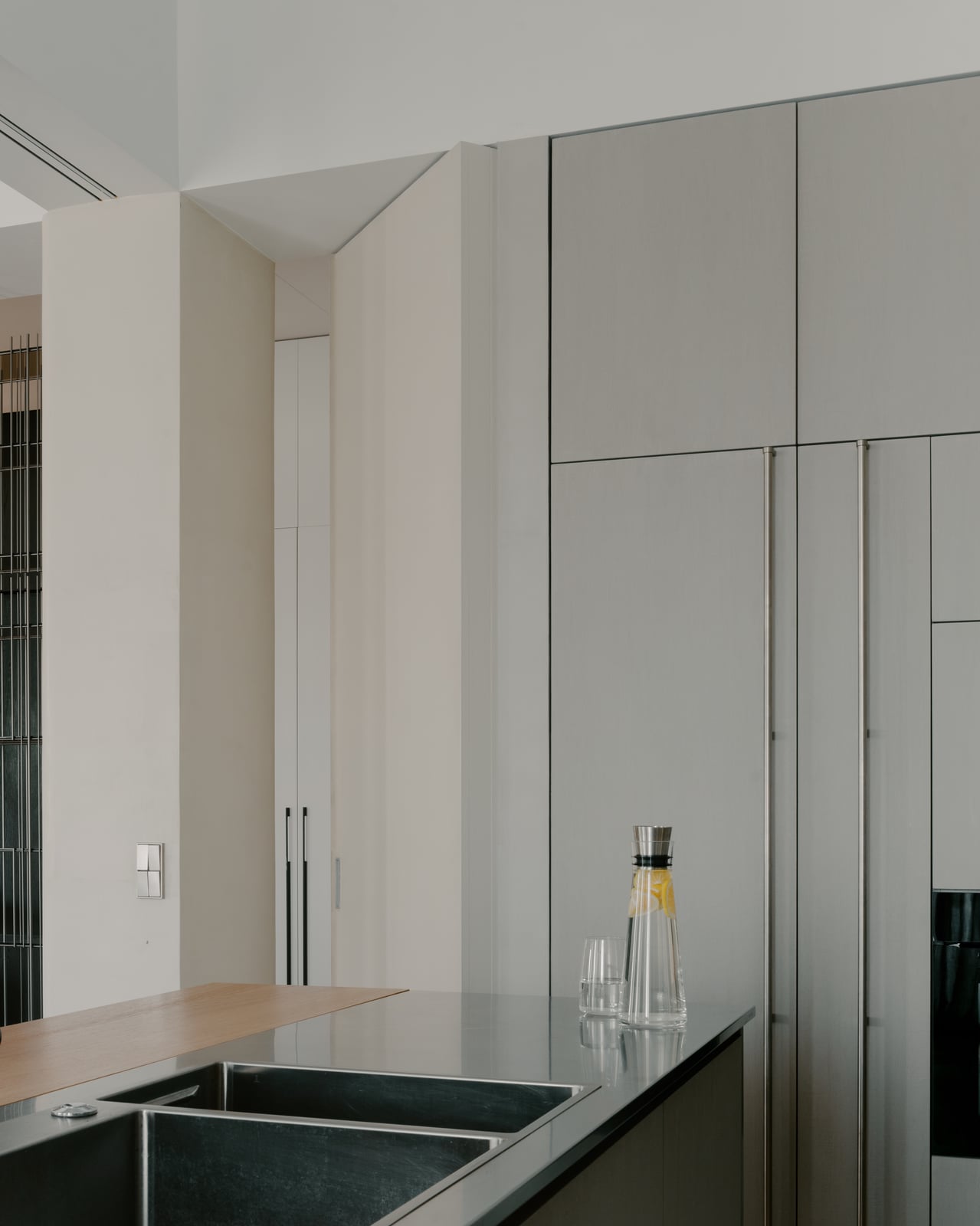 Kitchen sink set into a dark counter beside tall pale cabinetry