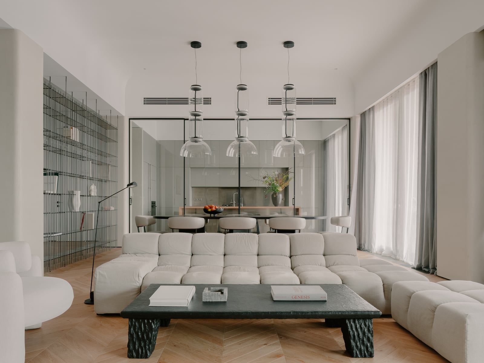 Living room with white modular sofas, a low black coffee table and a row of pendant lights
