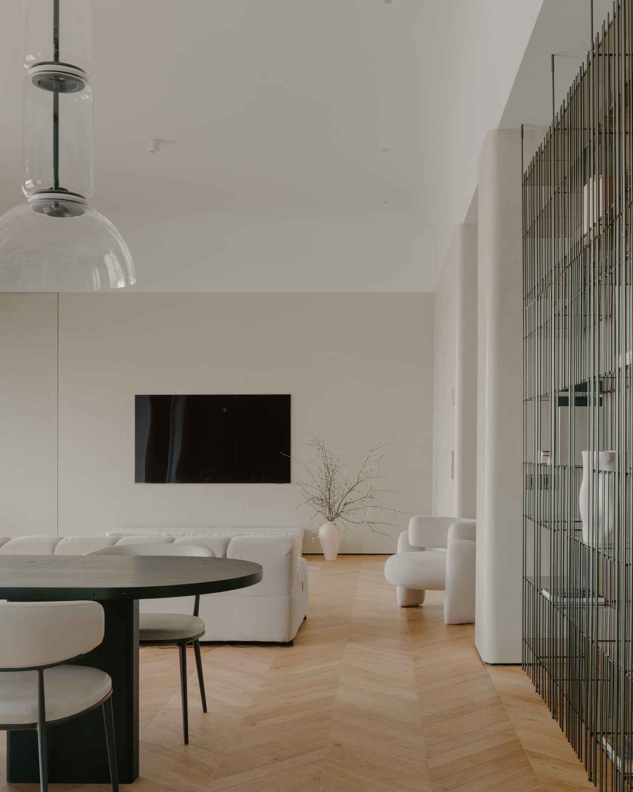 Living and dining area with a round table, glass pendant light and a reeded glass screen