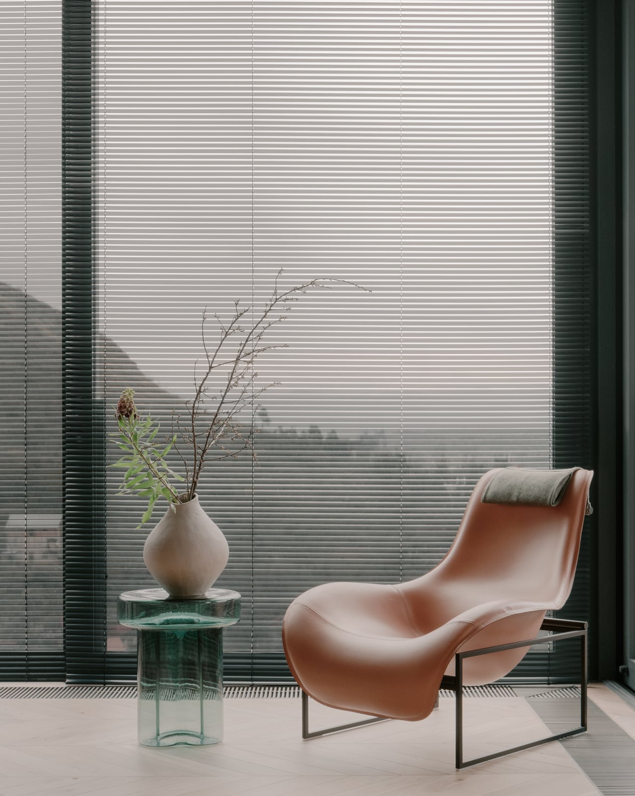 Floor-to-ceiling window with a leather lounge chair, a vase and a mountain view