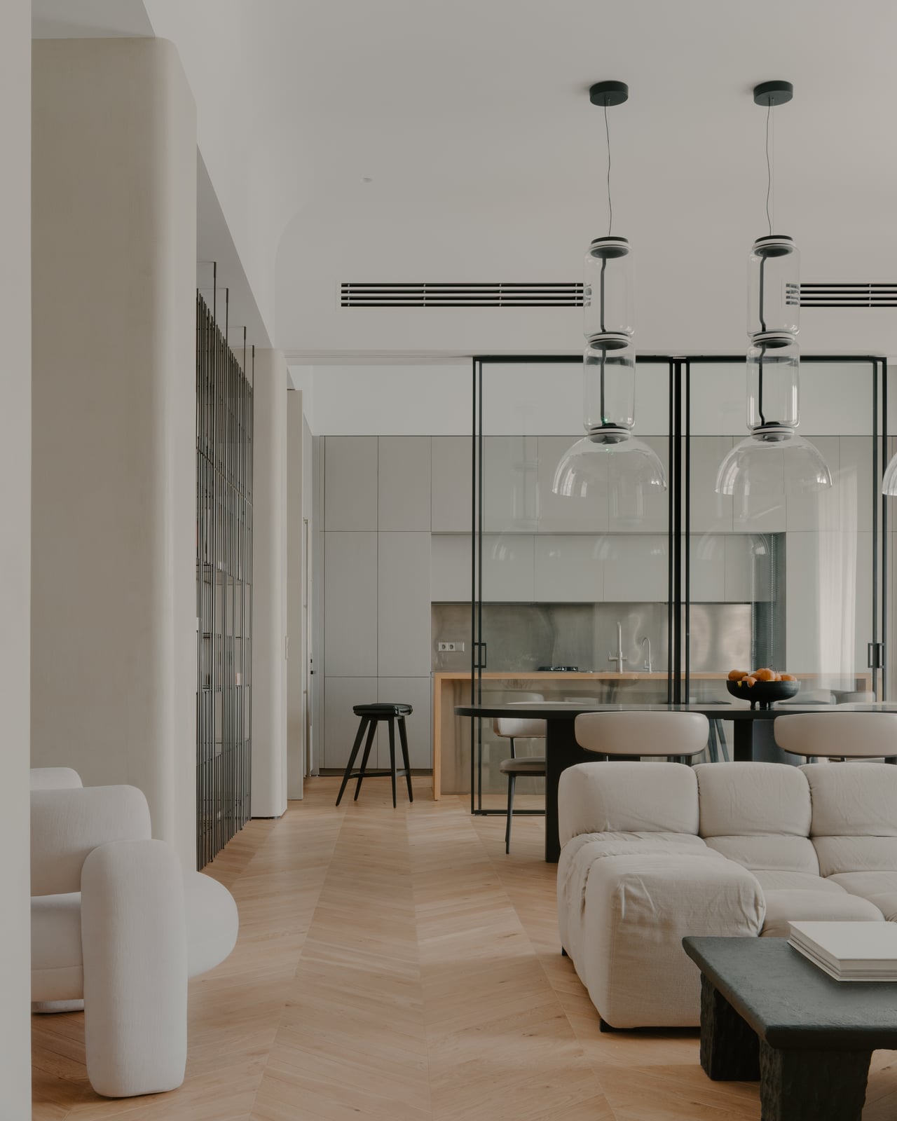 Living room and dining area with white sofas behind a glazed partition