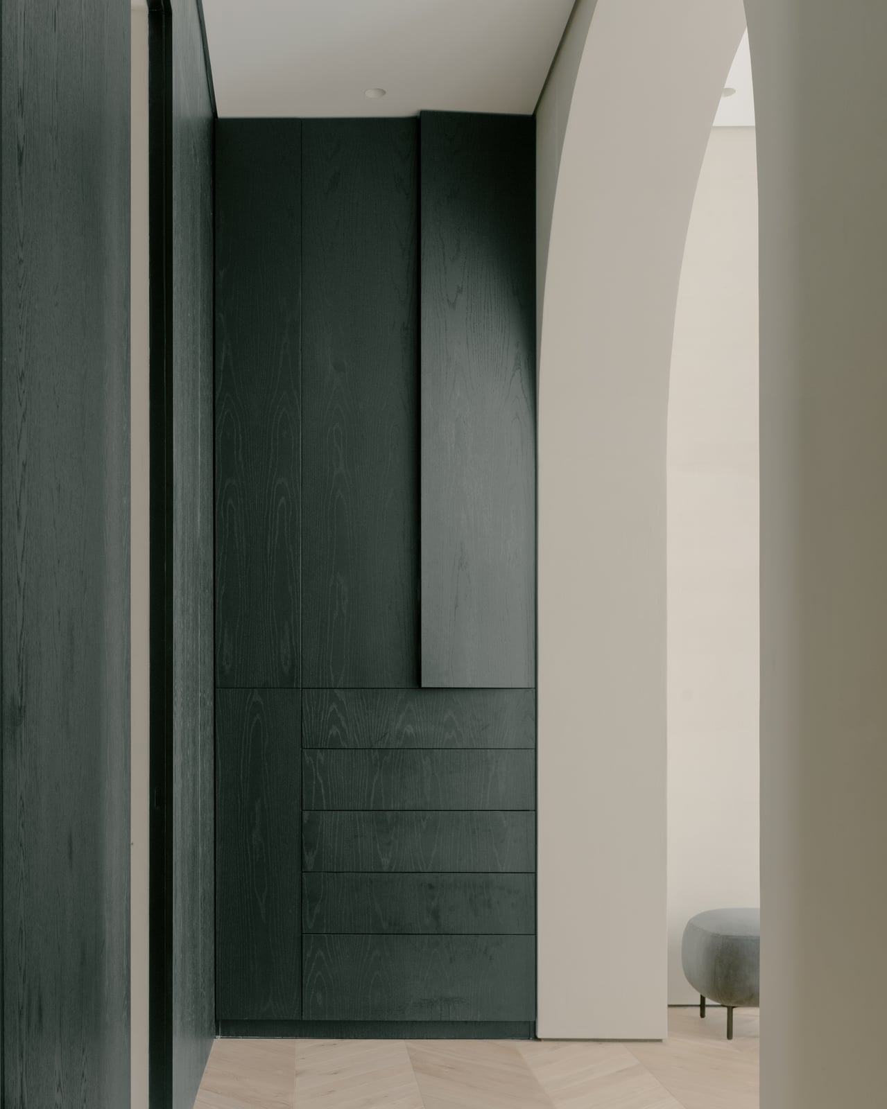 Dark timber door set into a white wall with a wall light beside it