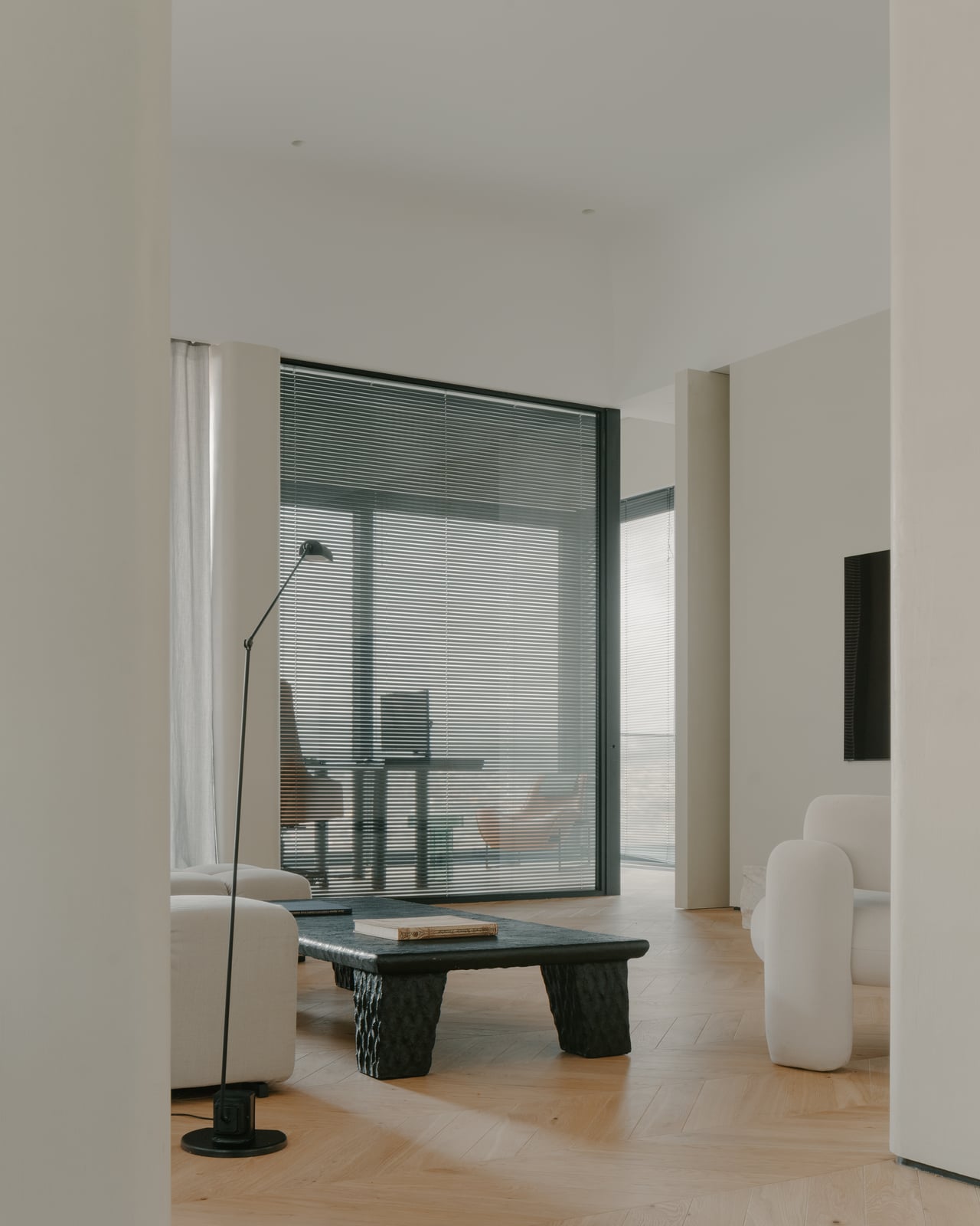 Living room with a floor lamp beside a full-height window wall