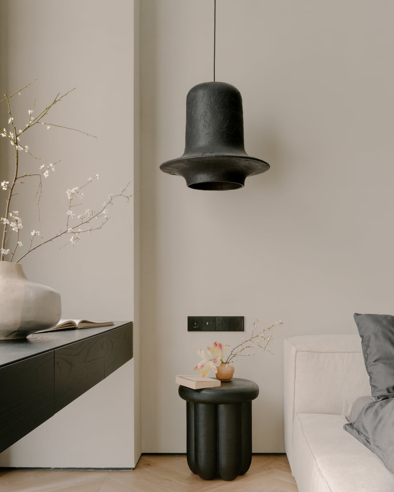 Bedroom detail: a black pendant light, a vase and branches on a black ledge