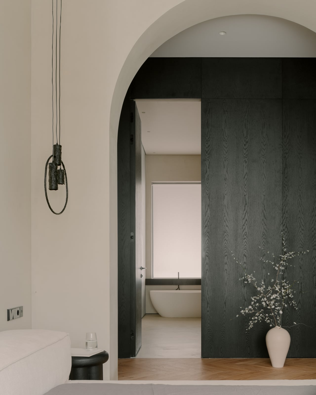 Arched opening to a bathroom with a freestanding tub and a tall vase