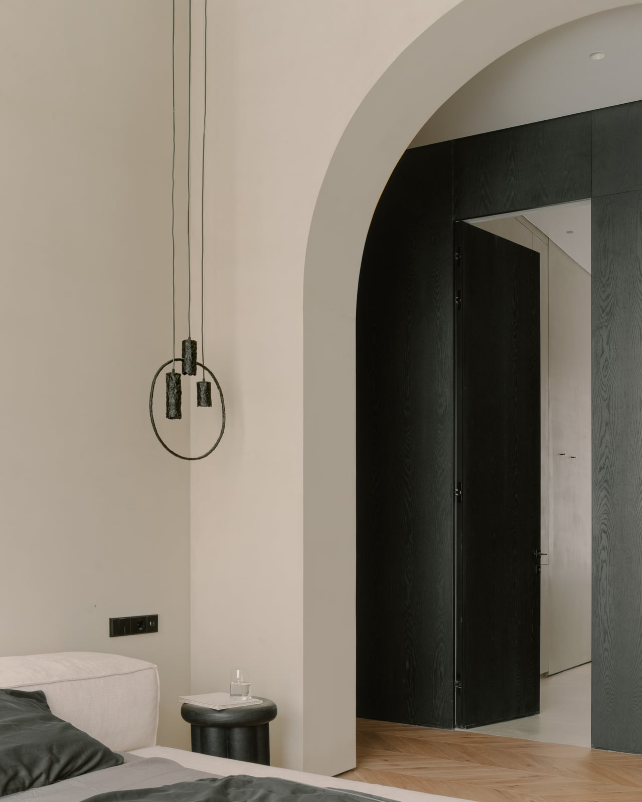 Bedroom with an arched opening to a dark dressing area and a pendant light