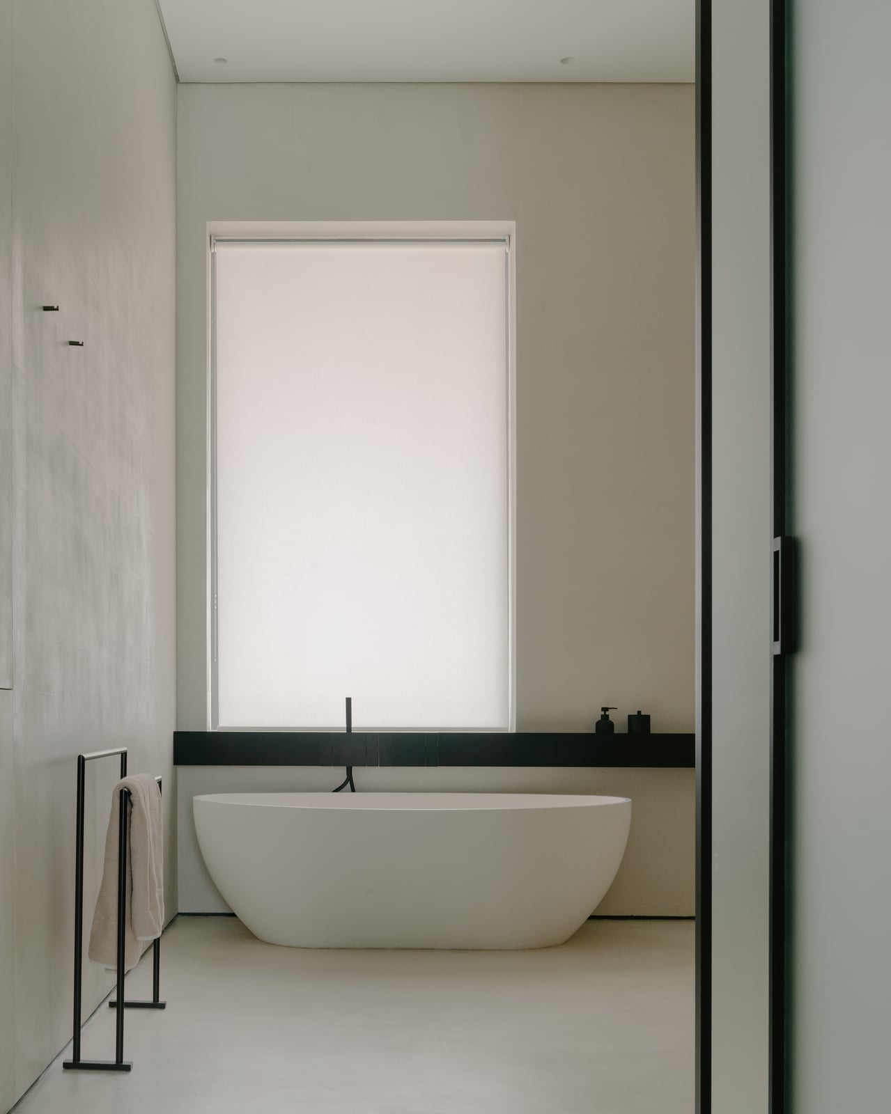 Bathroom with a freestanding tub and a black towel rail by a tall window