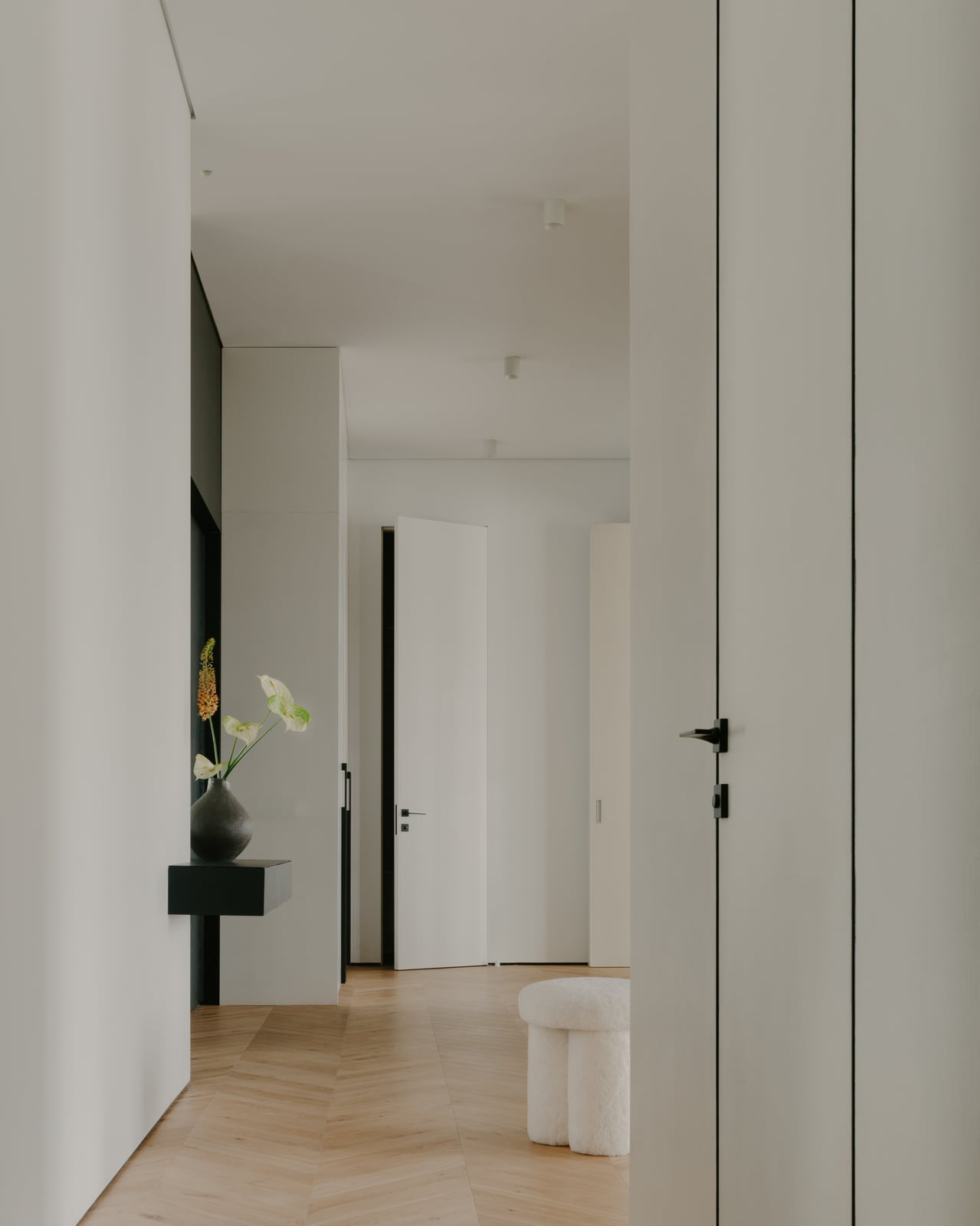 Corridor with pale doors and a black wall light